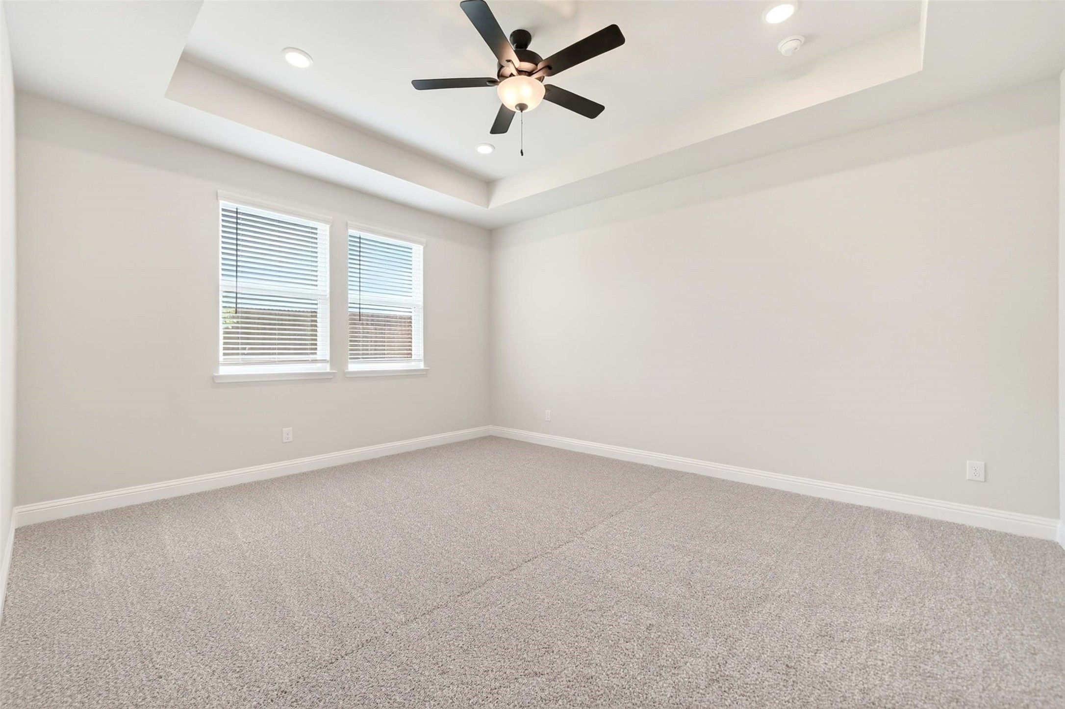 Spacious bedroom with tray ceiling and ceiling fan in The Holly C floor plan at Parks at Foster Crossing, Anna, Texas.