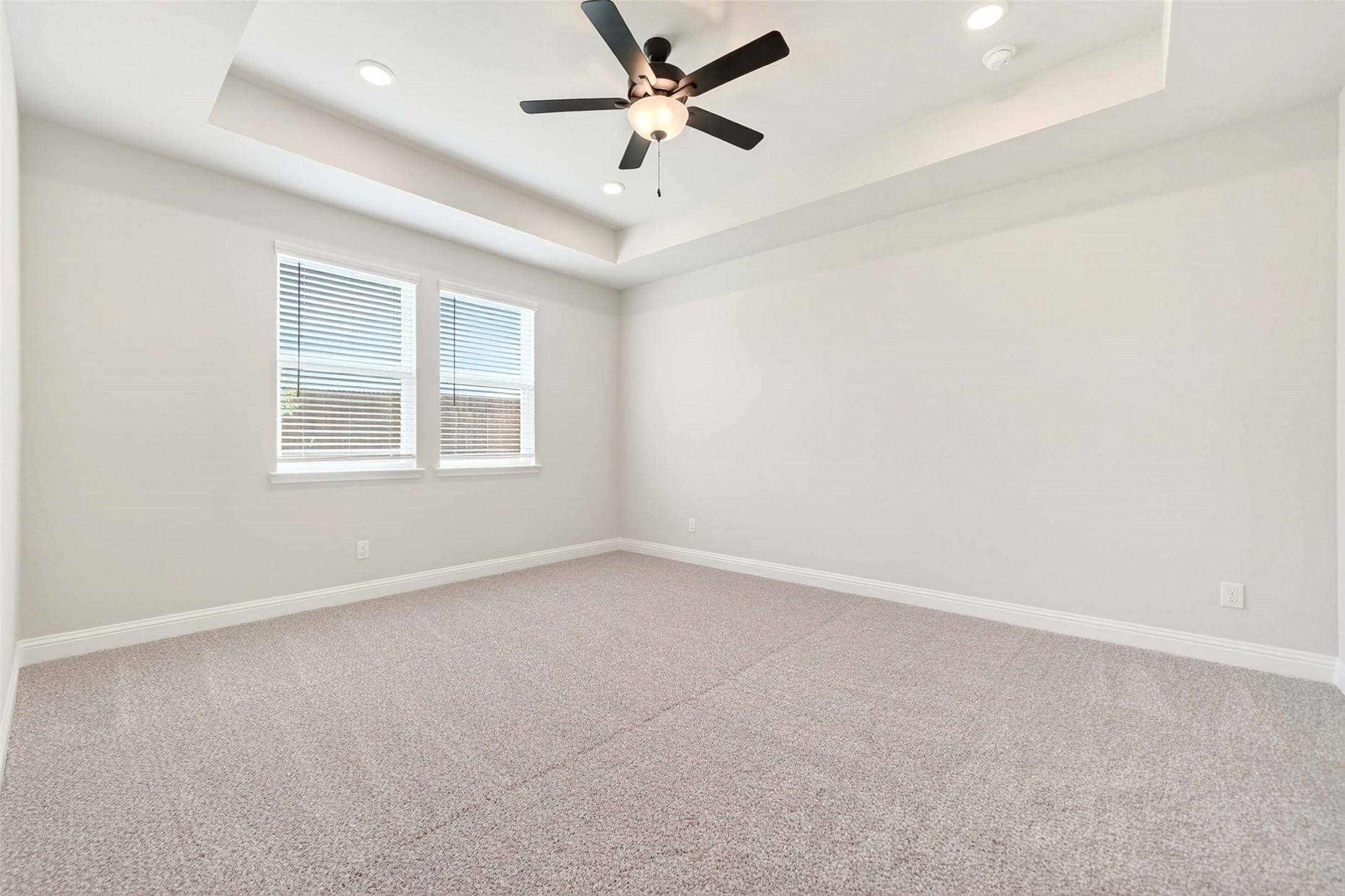 Spacious bedroom with tray ceiling and ceiling fan in The Holly C floor plan at Parks at Foster Crossing, Anna, Texas.