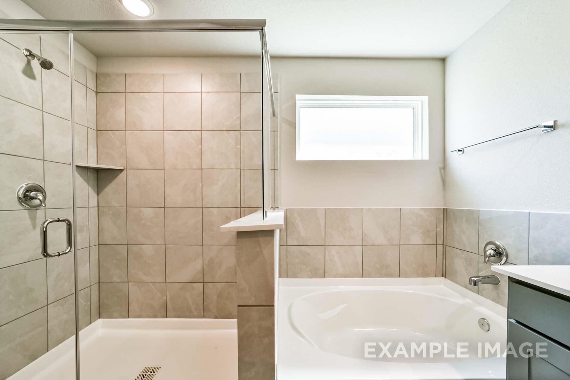 Modern bathroom with a tiled walk-in shower and soaking tub in The Riviera A floor plan at Emberly, Beasley, Texas.