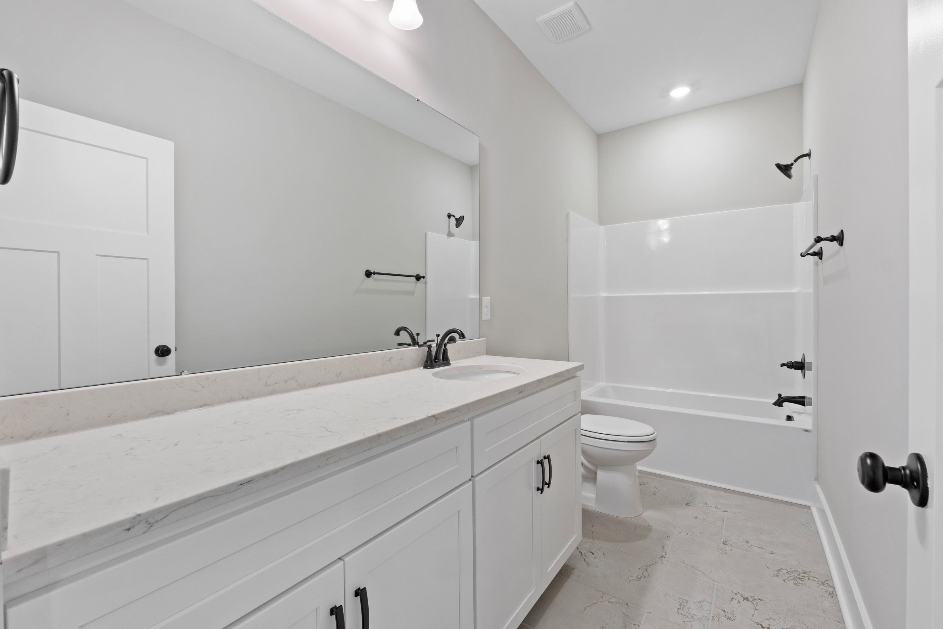 Spacious bathroom in The Oxford B by Evermore Homes with white shaker cabinets, quartz vanity, soaking tub, and glass shower