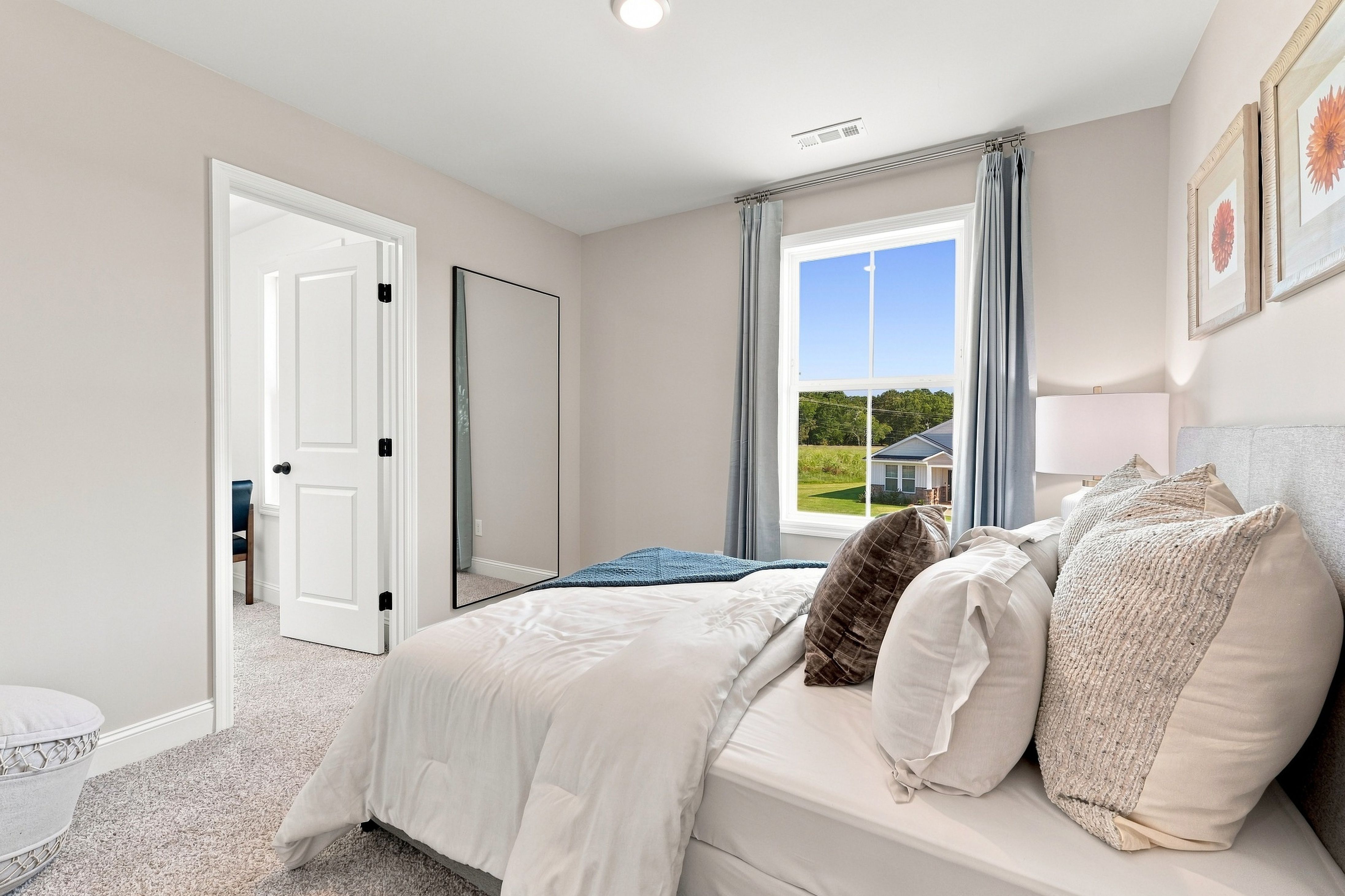 Bright neutral bedroom with large window at Bailey Park by Davidson Homes in Fayetteville, Tennessee