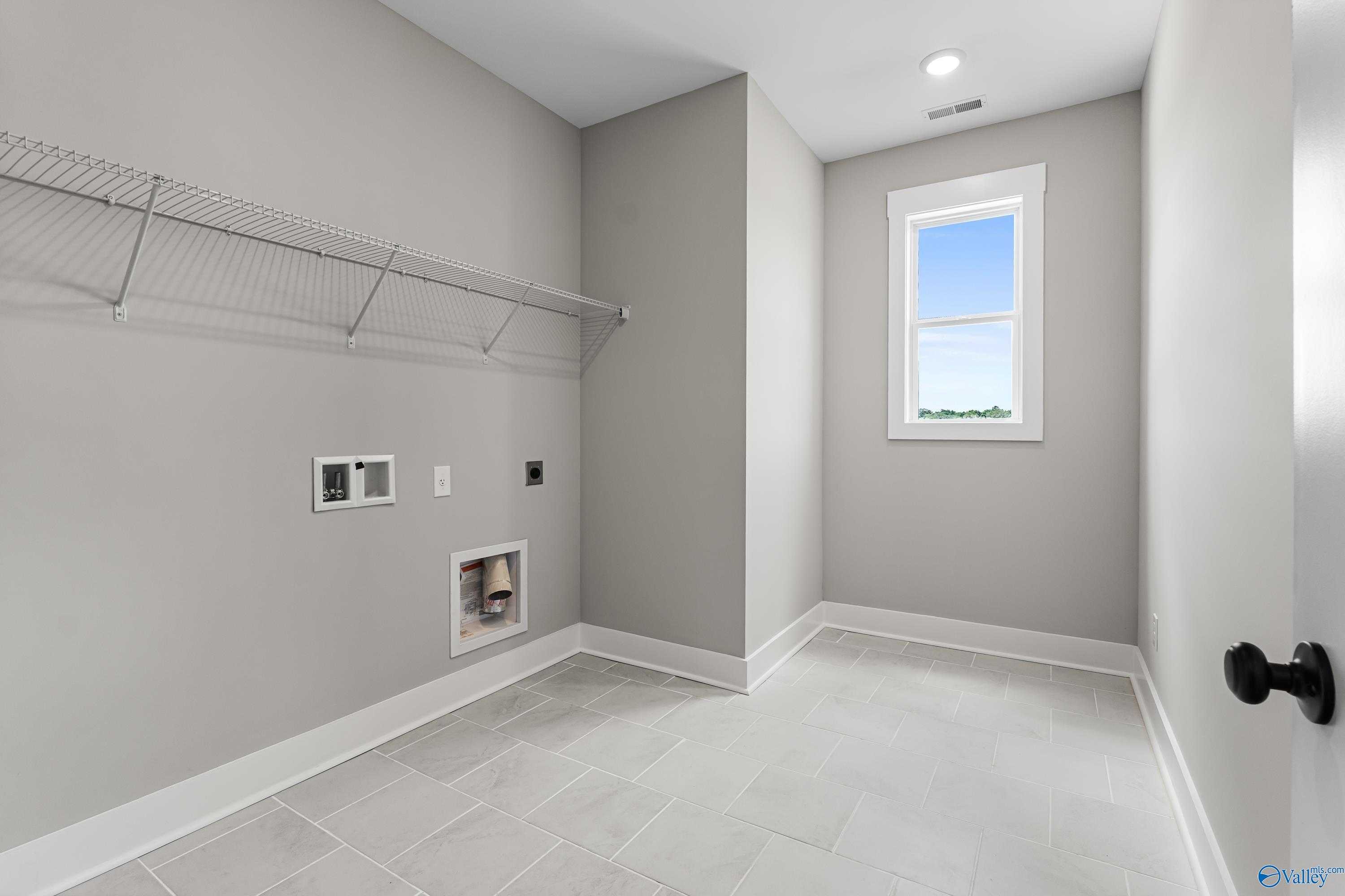 Modern laundry room with wire shelving, washer-dryer hookups, gray walls, tile floor in Davidson Homes The Arcadia, Huntsville AL