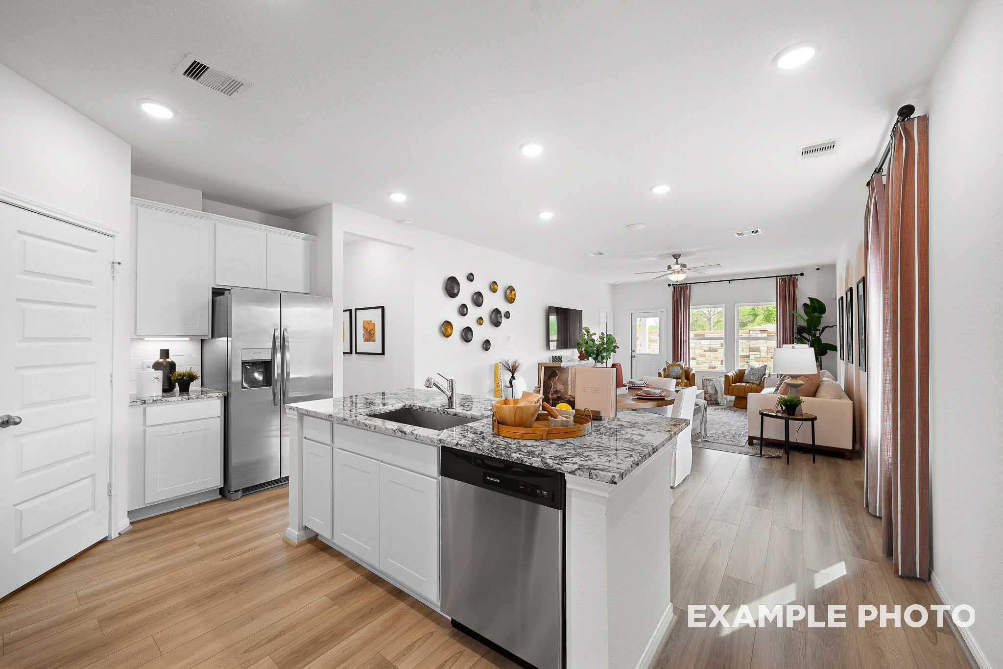 Spacious open-concept kitchen and living area in The Sabine F with white cabinetry, large granite island, stainless appliances