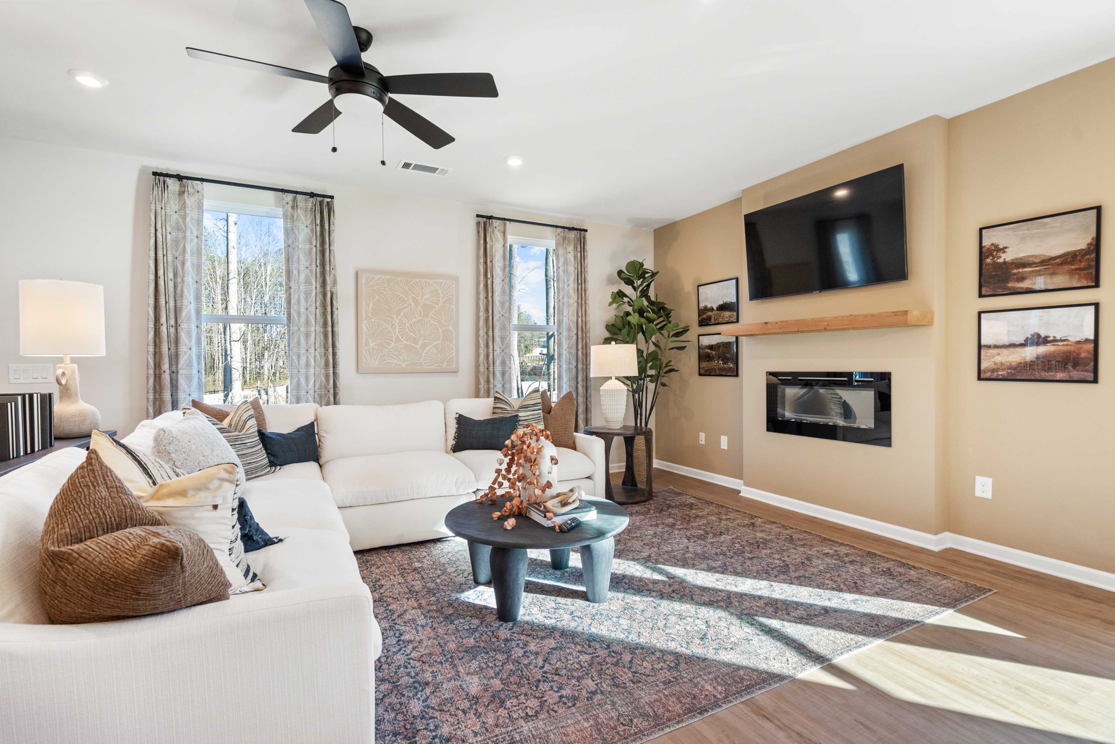 Spacious living room at The Village at Shallowford in Kennesaw GA with white sectional sofa, gas fireplace, ceiling fan, and hardwood floors