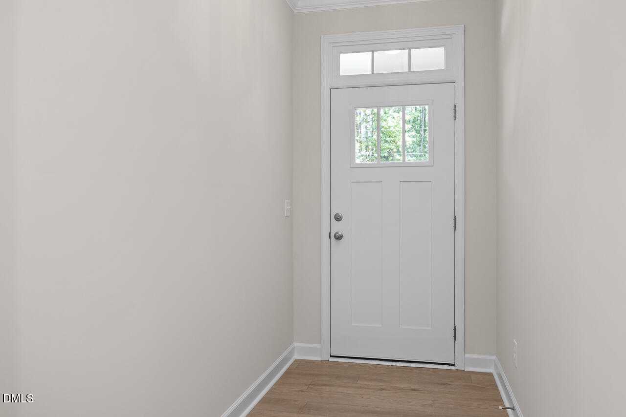 Bright hallway with white paneled door and transom window overlooking greenery in Davidson Homes The Beech C, Wake Forest, NC