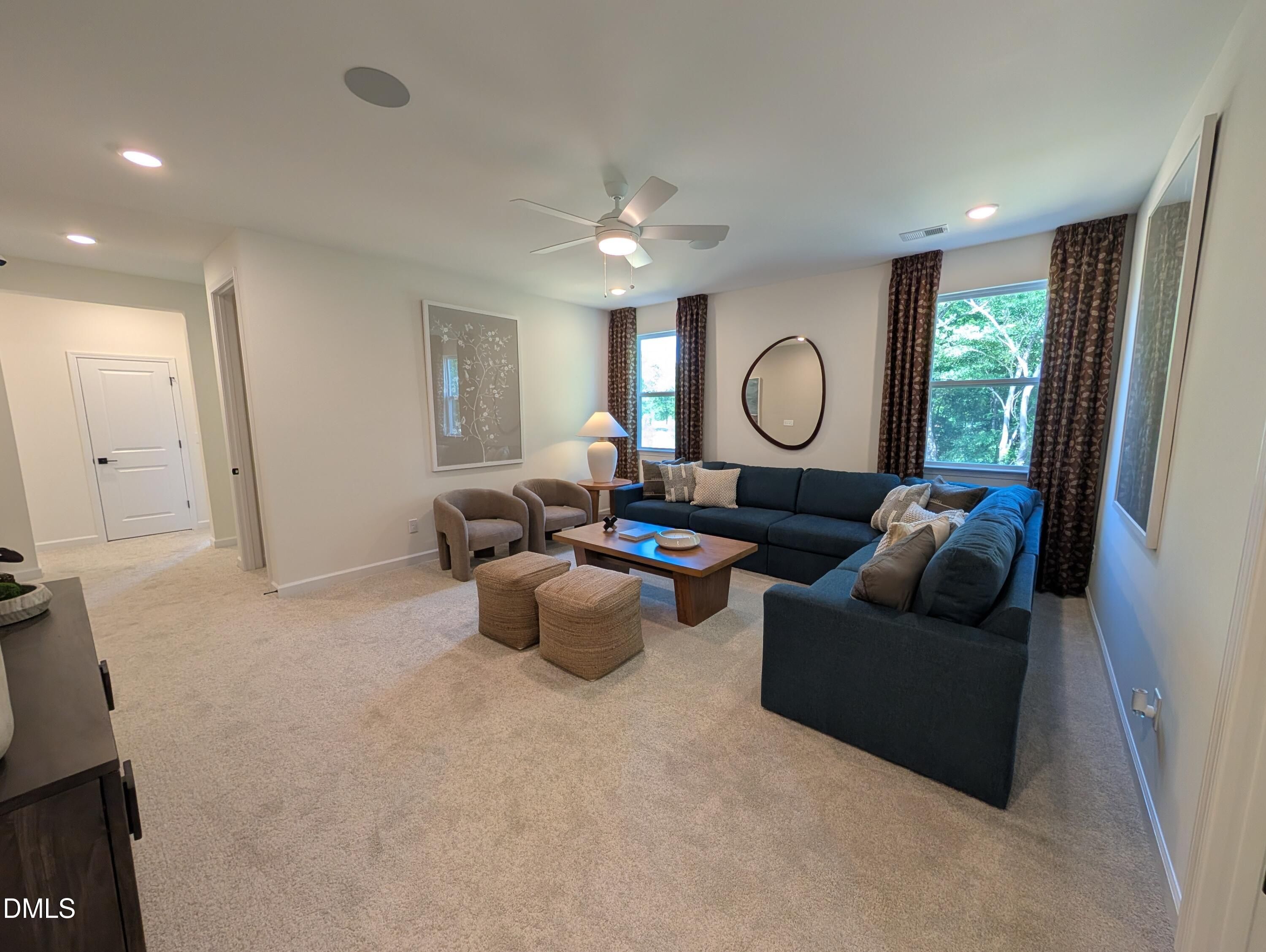 Spacious carpeted living room with blue sectional in The Aspen B floor plan at Wendell Ridge, Wendell, North Carolina.
