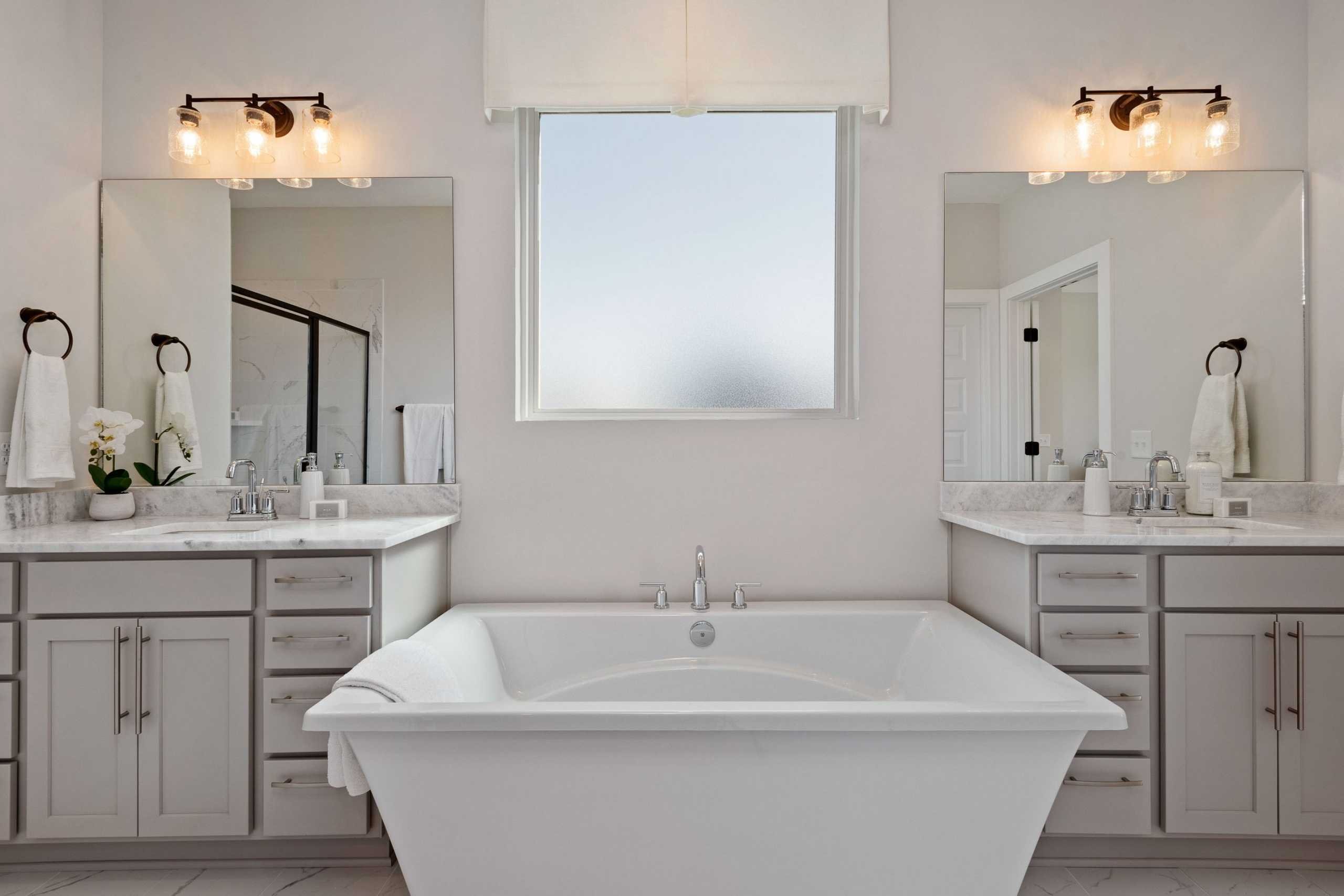 Elegant master bathroom at Rivers Edge in Murfreesboro TN with freestanding tub, double vanity, and frosted window