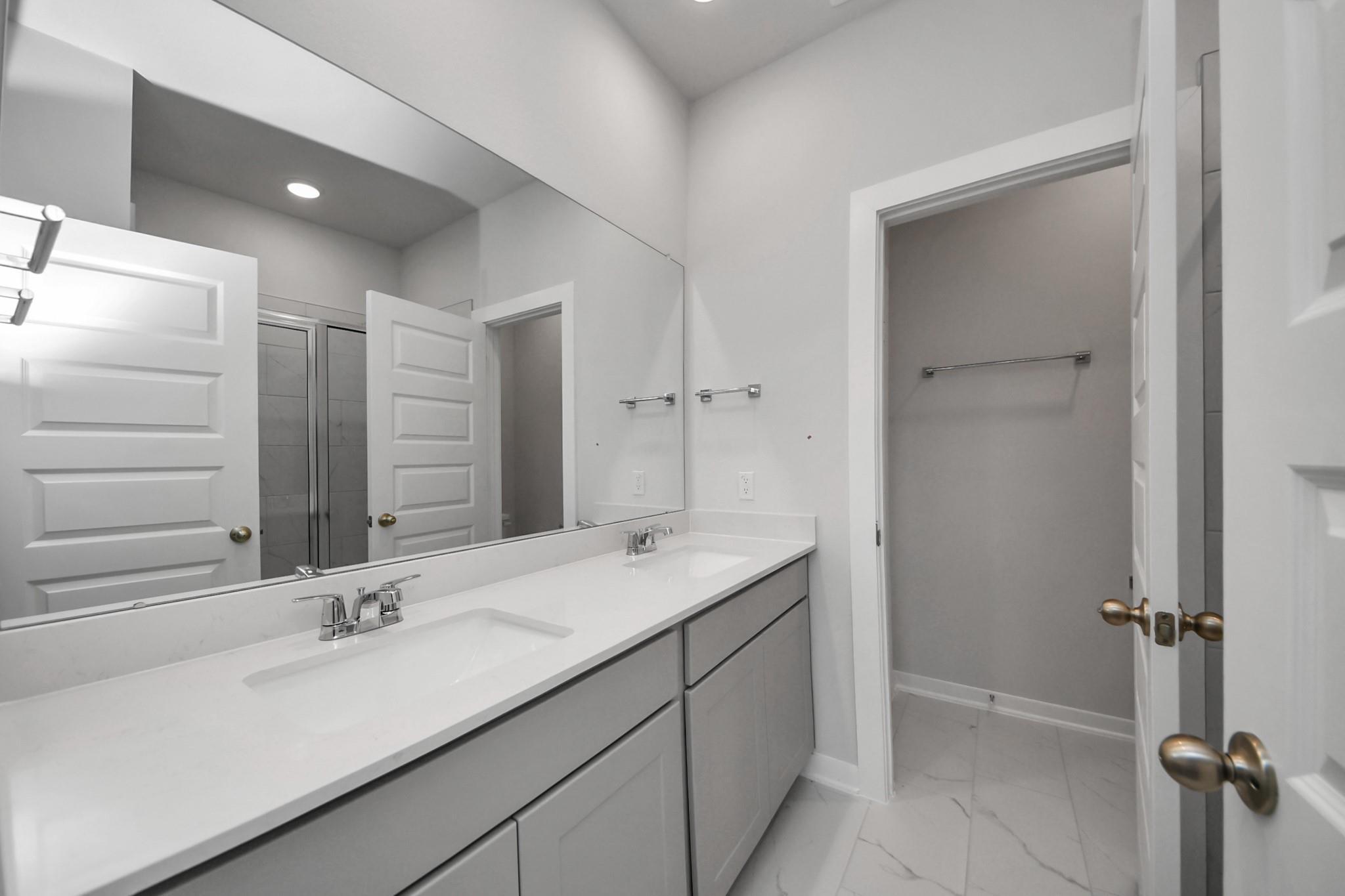 Double vanity bathroom with white countertops and large mirror in Davidson Homes The Frio F plan, Robins Landing Houston