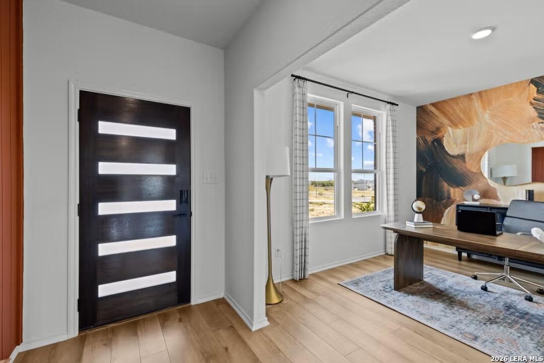 Modern home office with striped door, large window view, mural wall, wooden desk in Davidson Homes The Douglas C, Converse, TX