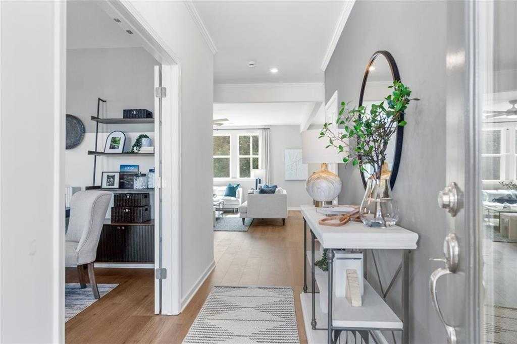 Elegant foyer with console table, large round mirror, and greenery leading to home office and living room in Davidson Homes Hickory B, Hoschton, GA
