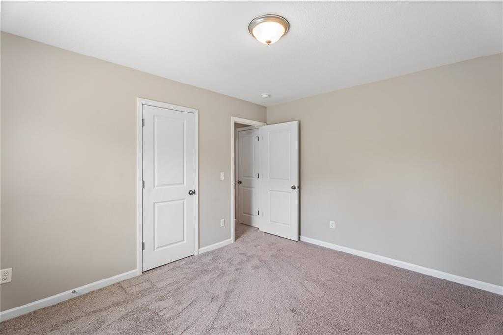 Neutral beige bedroom with plush carpet, white doors to adjacent bath, ceiling light in Davidson Homes The Bartlett, Phenix City, AL