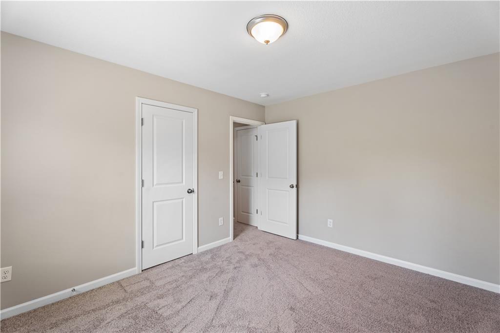 Neutral beige bedroom with plush carpet, white doors to adjacent bath, ceiling light in Davidson Homes The Bartlett, Phenix City, AL