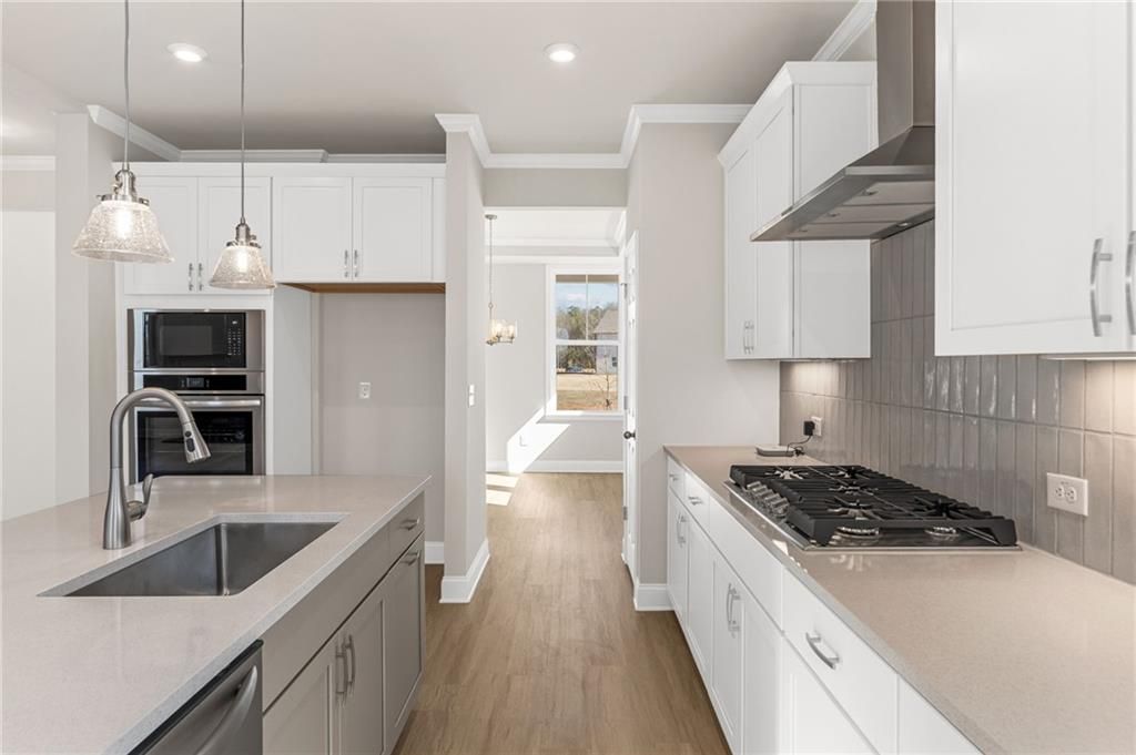 Modern white kitchen with quartz island, gas range, subway tile backsplash in Davidson Homes The Willow B, Hoschton GA