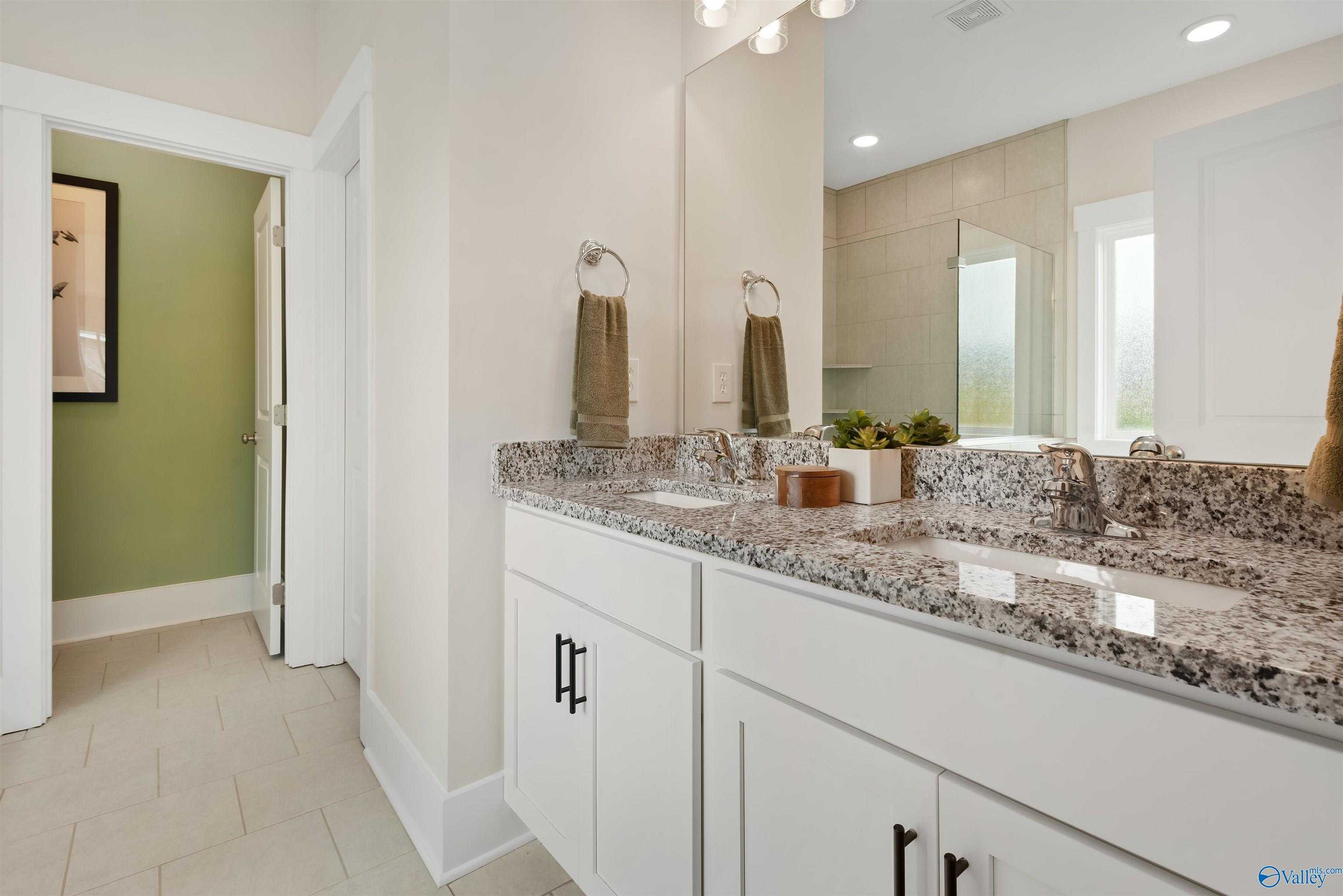 Elegant master bathroom with double vanity, granite counters, white cabinets in Davidson Homes The Daphne, Harvest, AL