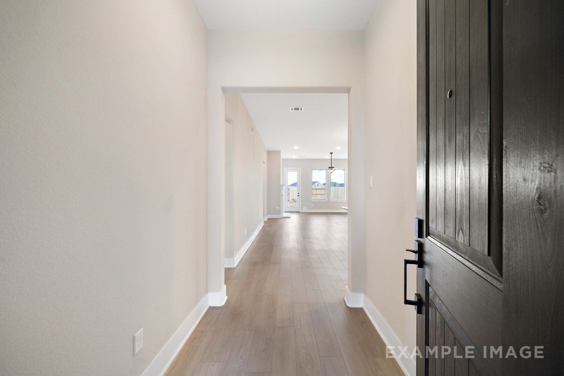 Foyer entry of The Elizabeth by Davidson Homes with dark wood front door and hardwood floors leading to open living area