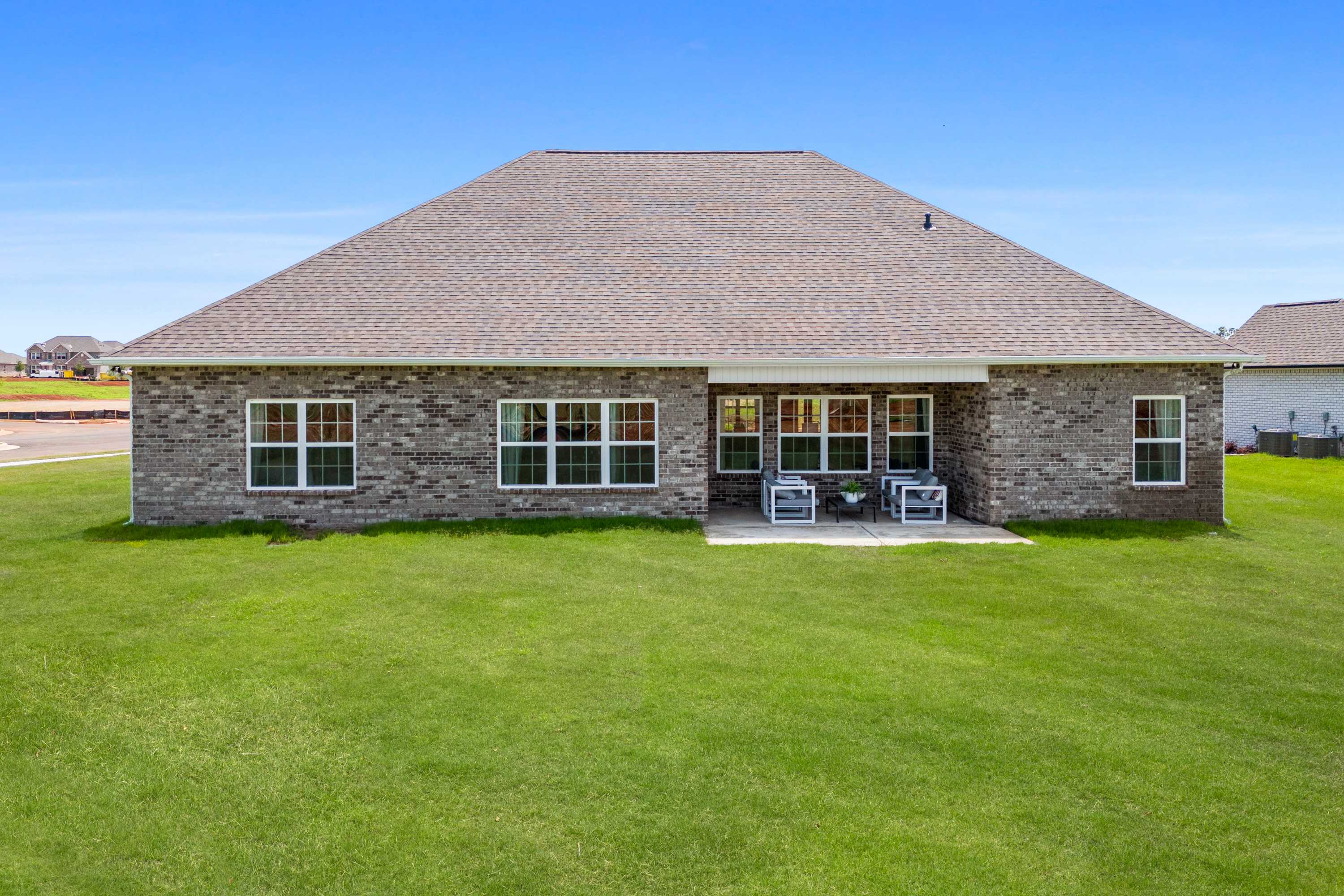 Brick ranch home exterior at Creekside in Harvest Alabama with covered patio seating and lush green lawn