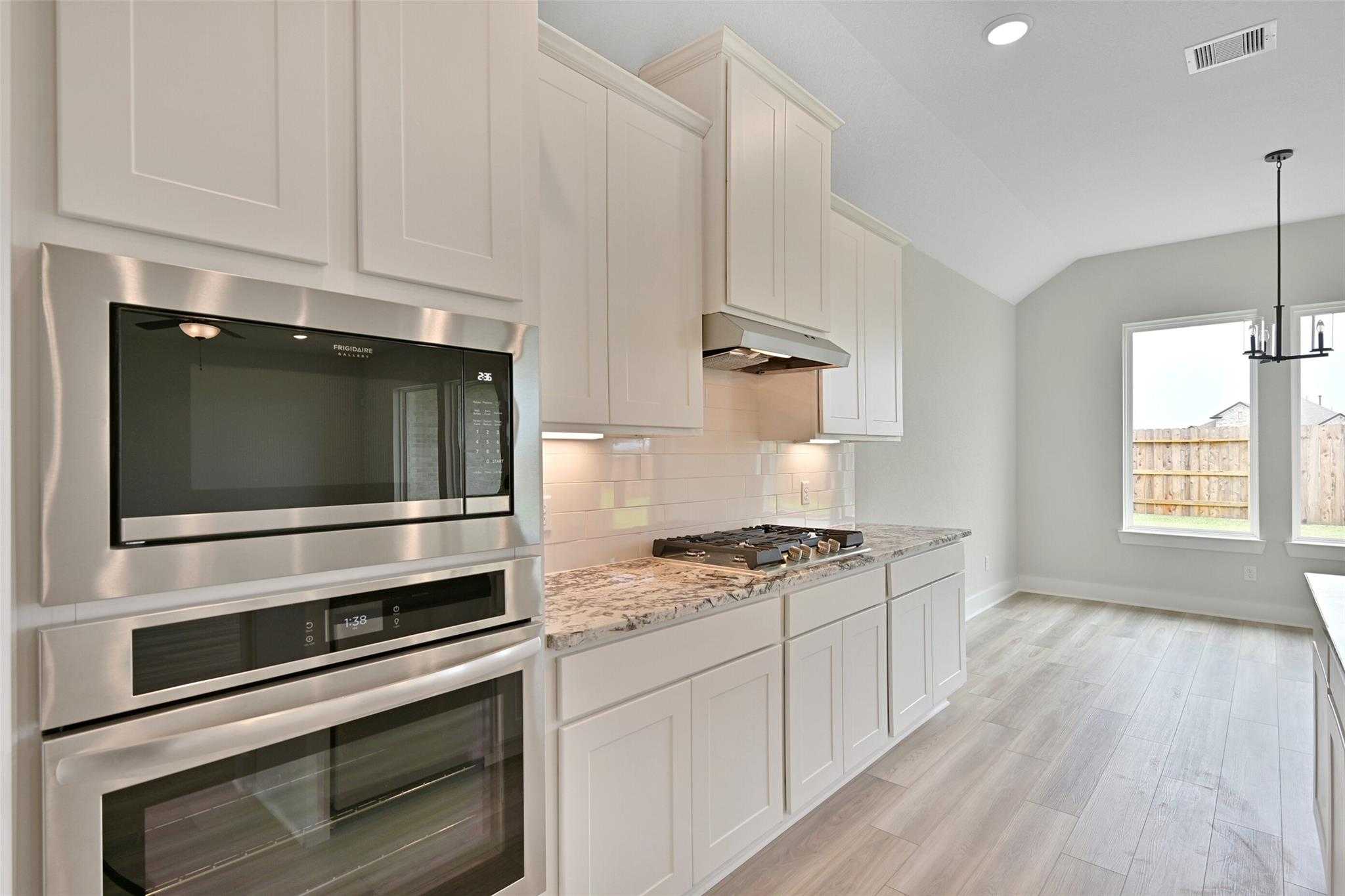 Modern white shaker kitchen with stainless double oven, quartz counters, gas cooktop in Davidson Homes The Edward C, Lago Mar, Texas City