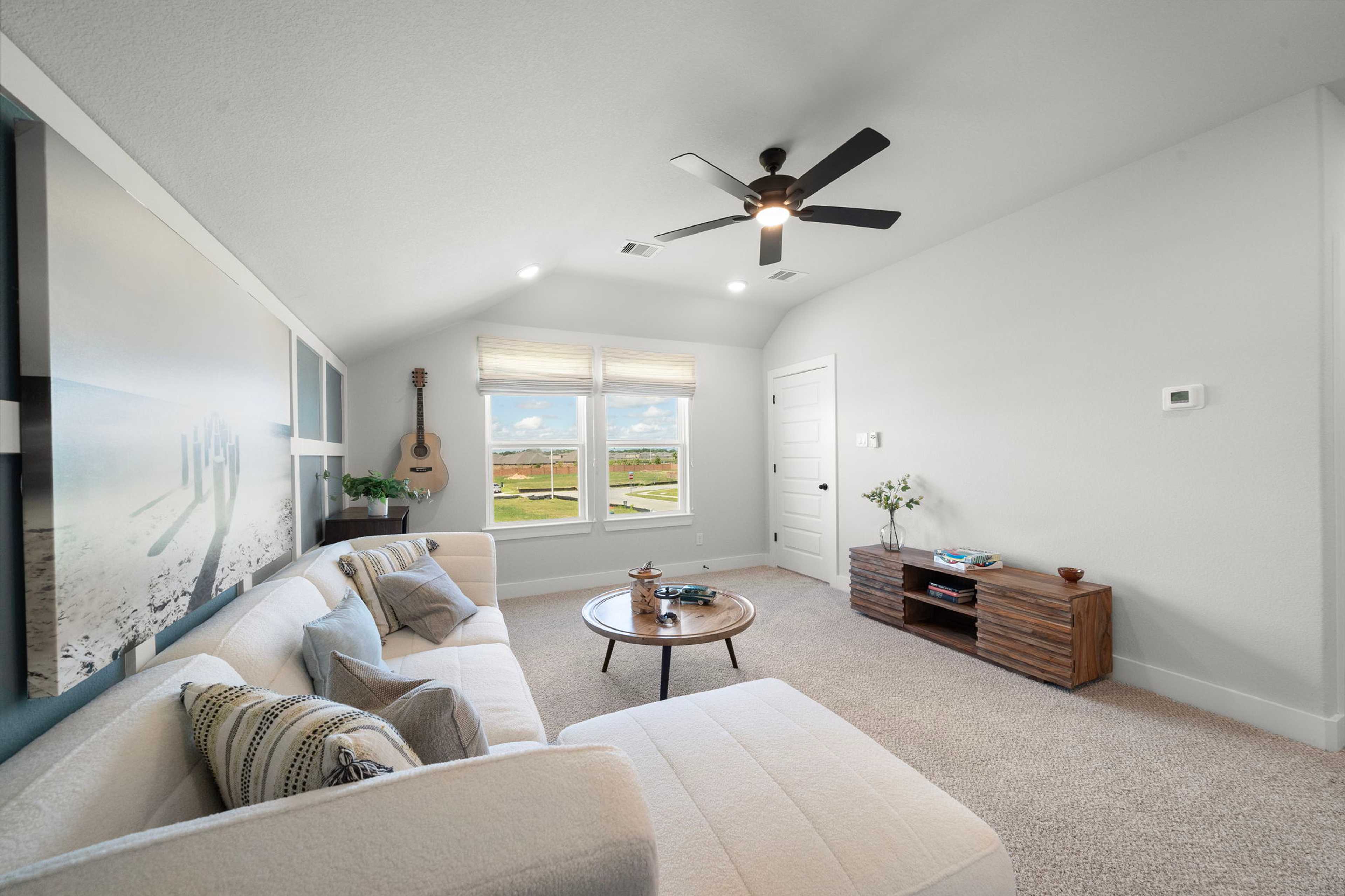 Cozy loft bonus room at Lago Mar in Texas City Texas with white sectional sofa, ceiling fans, guitar decor, and golf course views