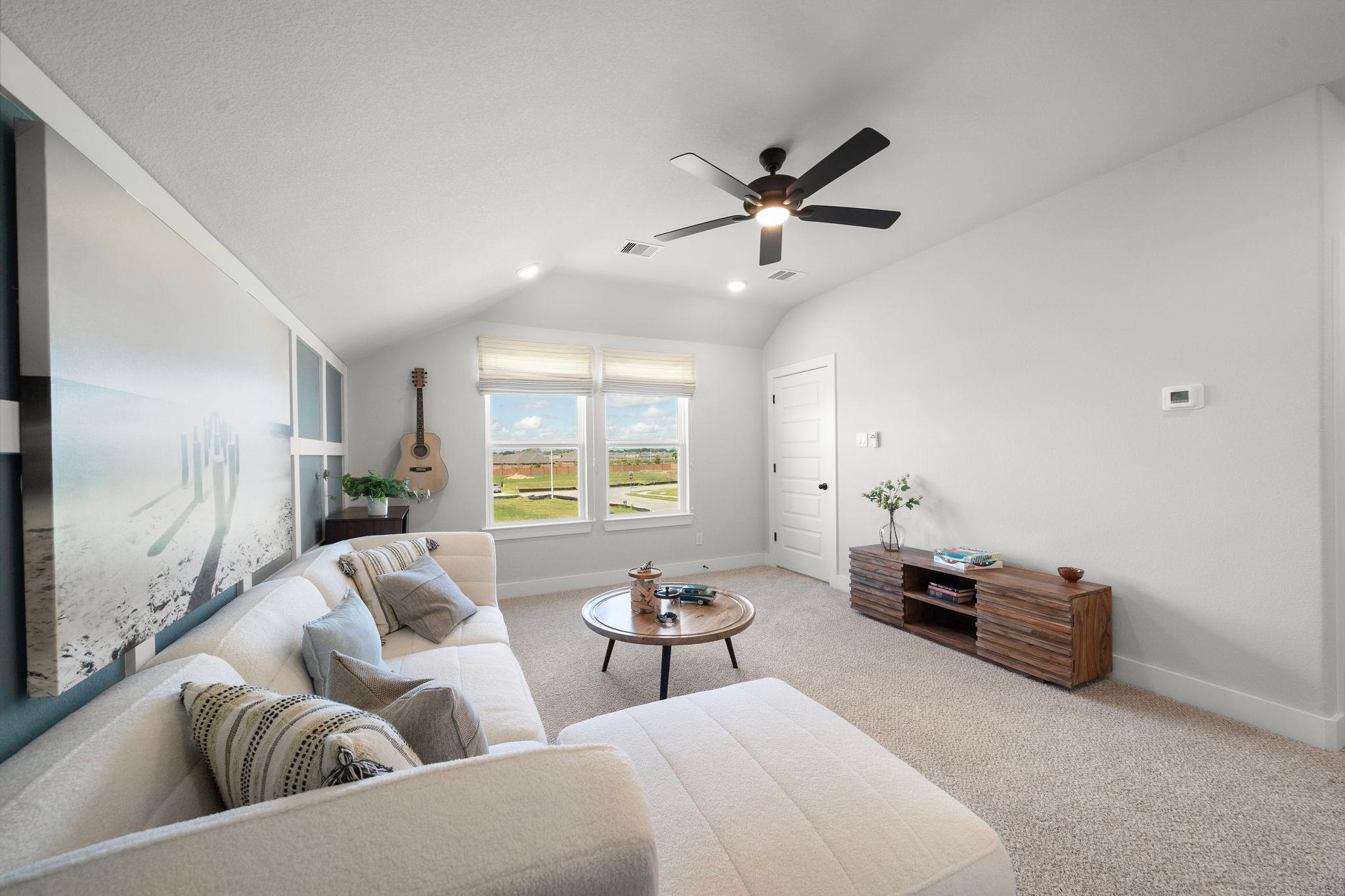 Cozy loft bonus room at Lago Mar in Texas City Texas with white sectional sofa, ceiling fans, guitar decor, and golf course views