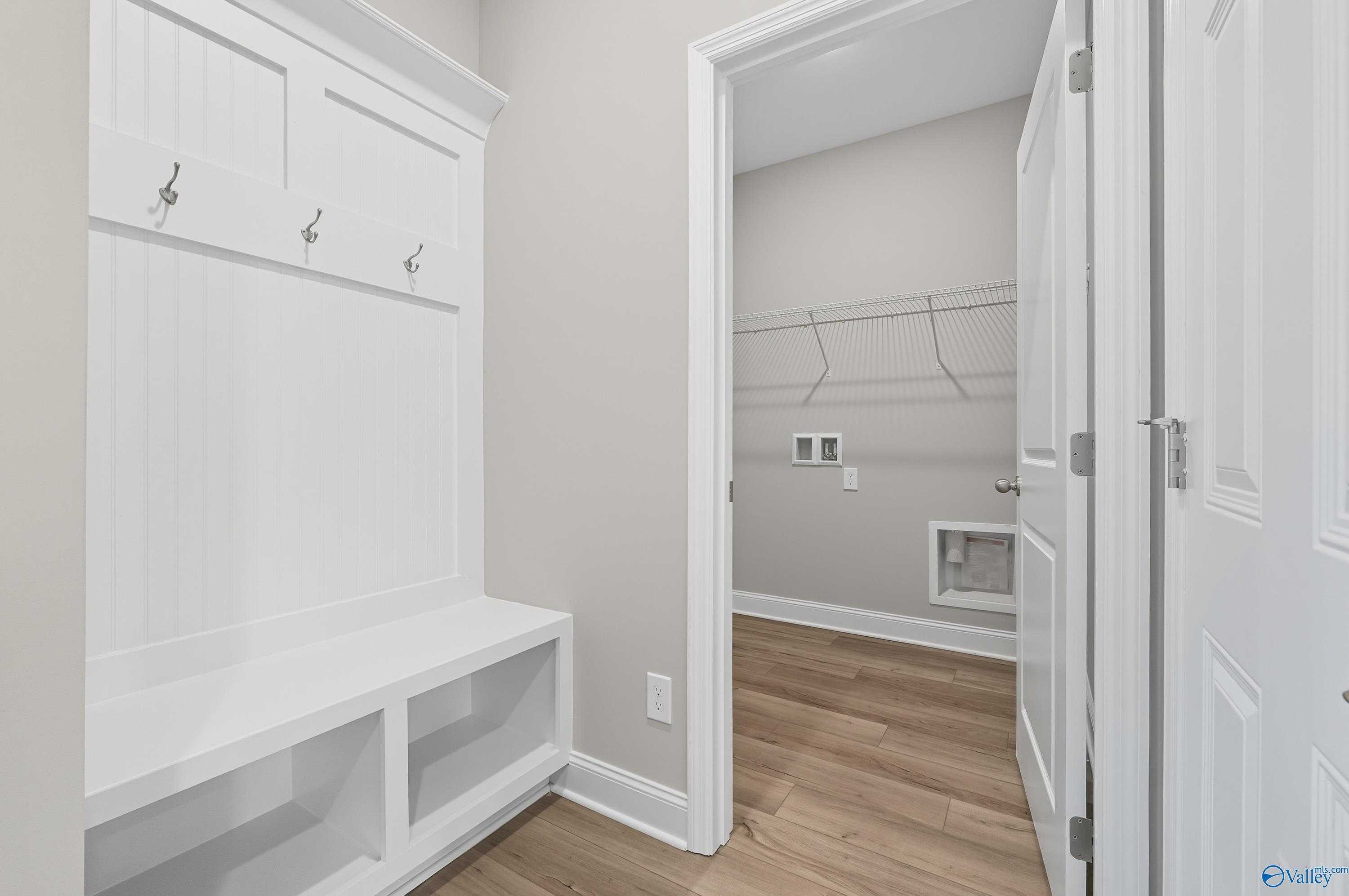 White mudroom with beadboard cabinetry, coat hooks, built-in bench, and laundry hookups in Davidson Homes The Franklin, Meridianville, Alabama