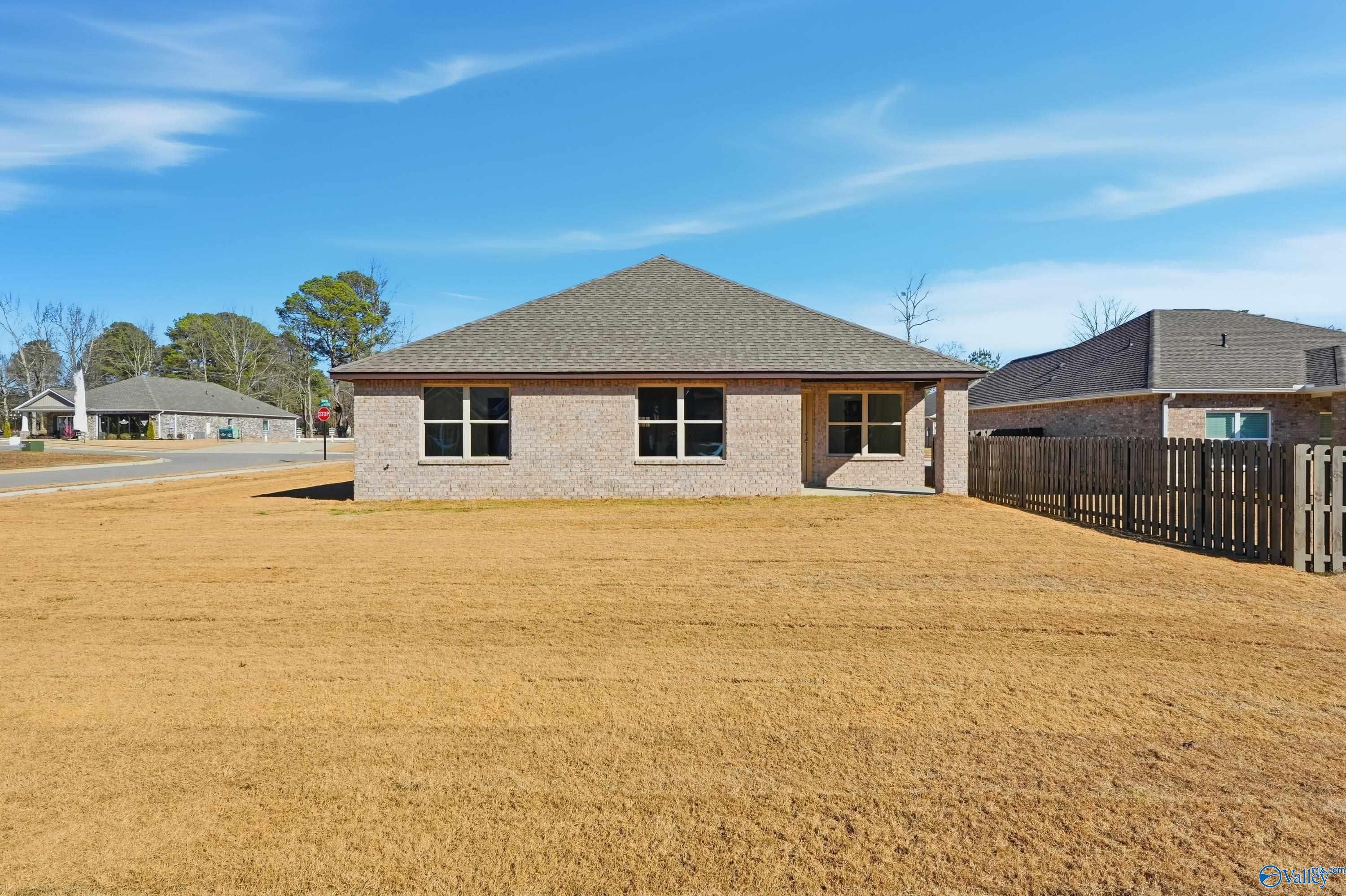 Brick single-story 4-bedroom home with gabled roof, large windows, and fenced yard in The Highlands, Arab, Alabama by Davidson Homes The Daphne C