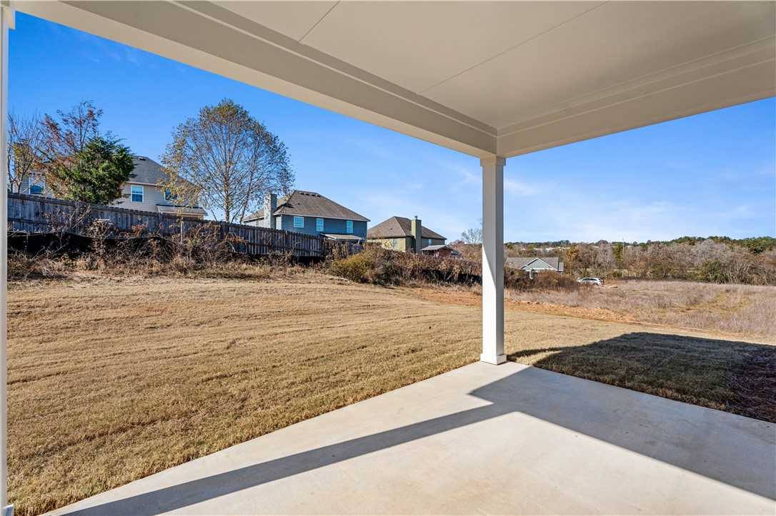 Covered back patio with concrete flooring overlooking grassy yard and neighboring homes in Anderson Lakes, Opelika, Alabama