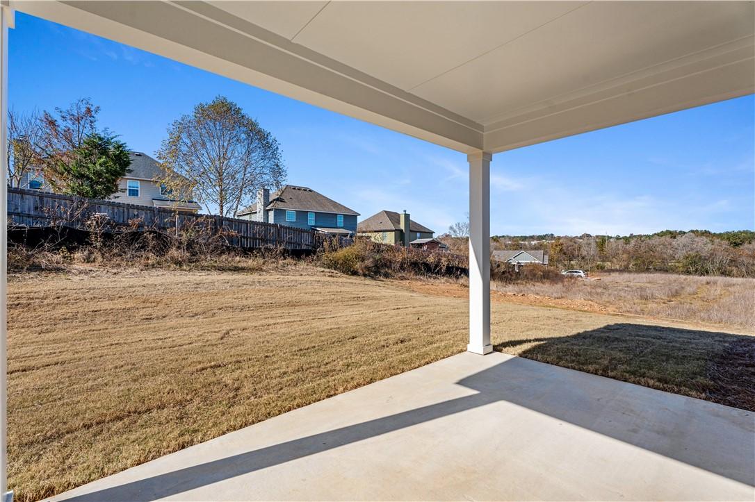 Covered back patio with concrete flooring overlooking grassy yard and neighboring homes in Anderson Lakes, Opelika, Alabama