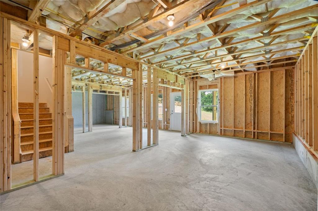 Unfinished basement framing with wooden studs, stairs, and pink insulation in Davidson Homes The Willow B, Hoschton, Georgia