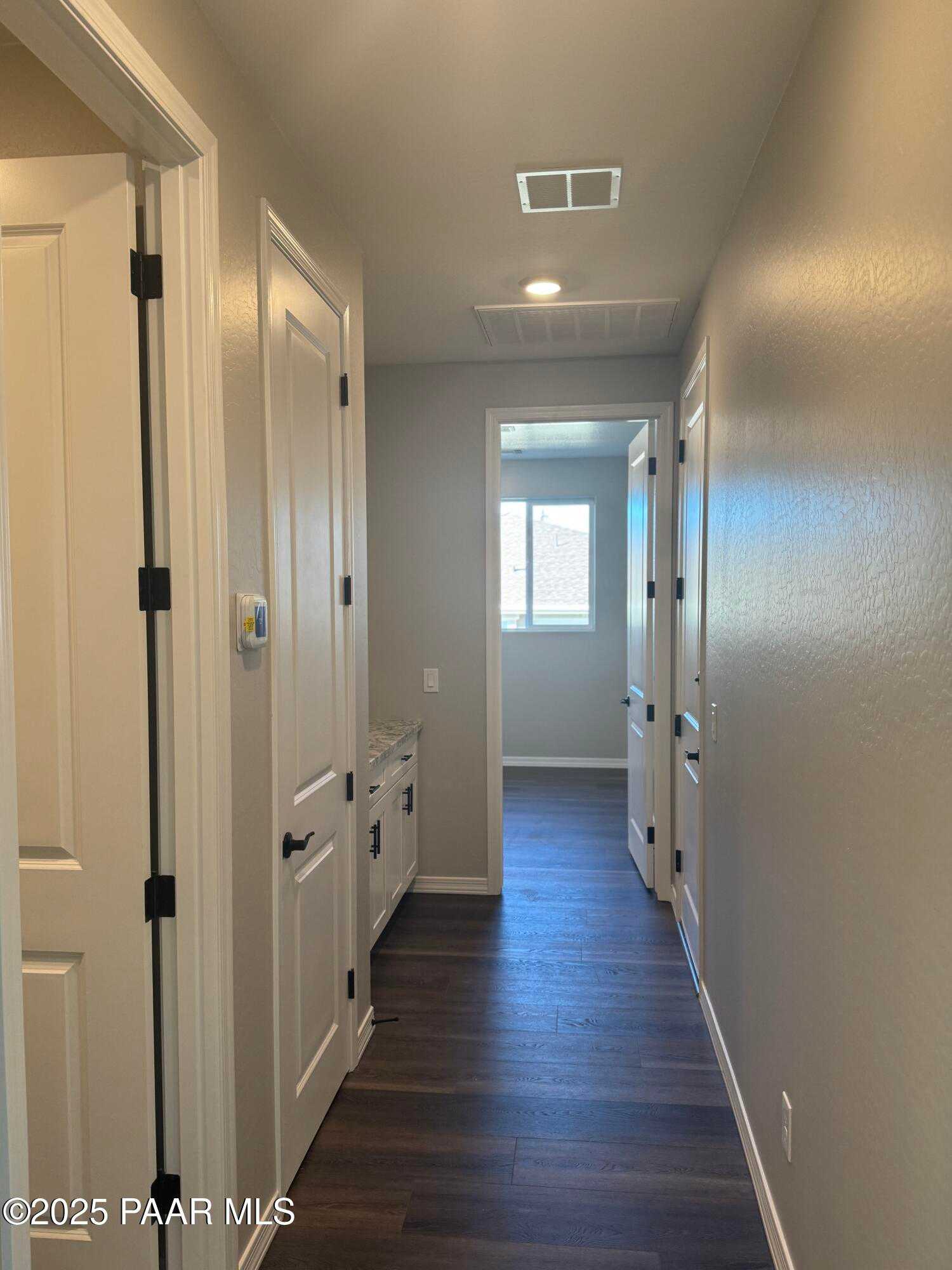Spacious hallway with hardwood floors, white doors, and window view in 3-bedroom Davidson Homes The Monarch E, Prescott AZ