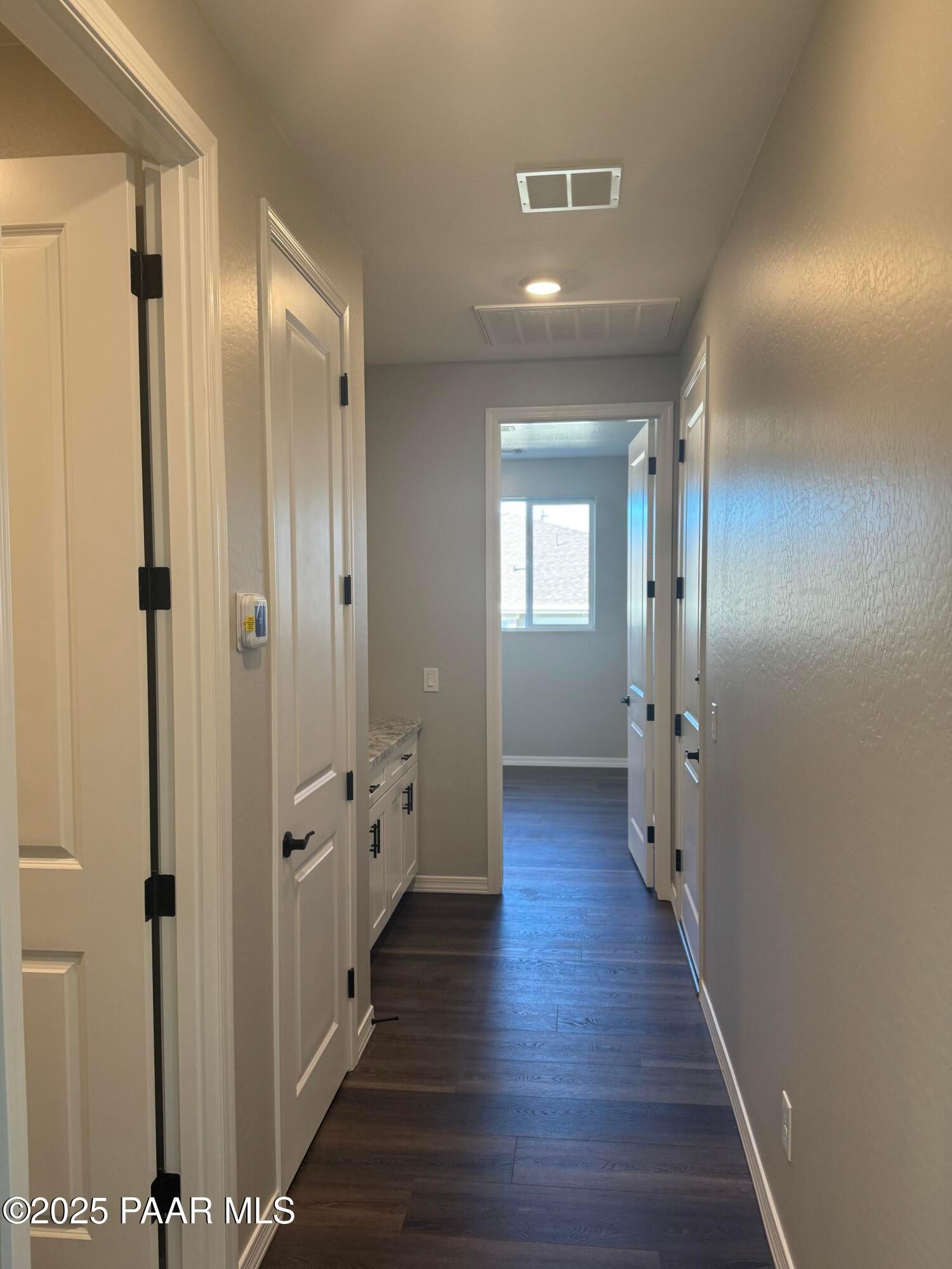 Spacious hallway with hardwood floors, white doors, and window view in 3-bedroom Davidson Homes The Monarch E, Prescott AZ
