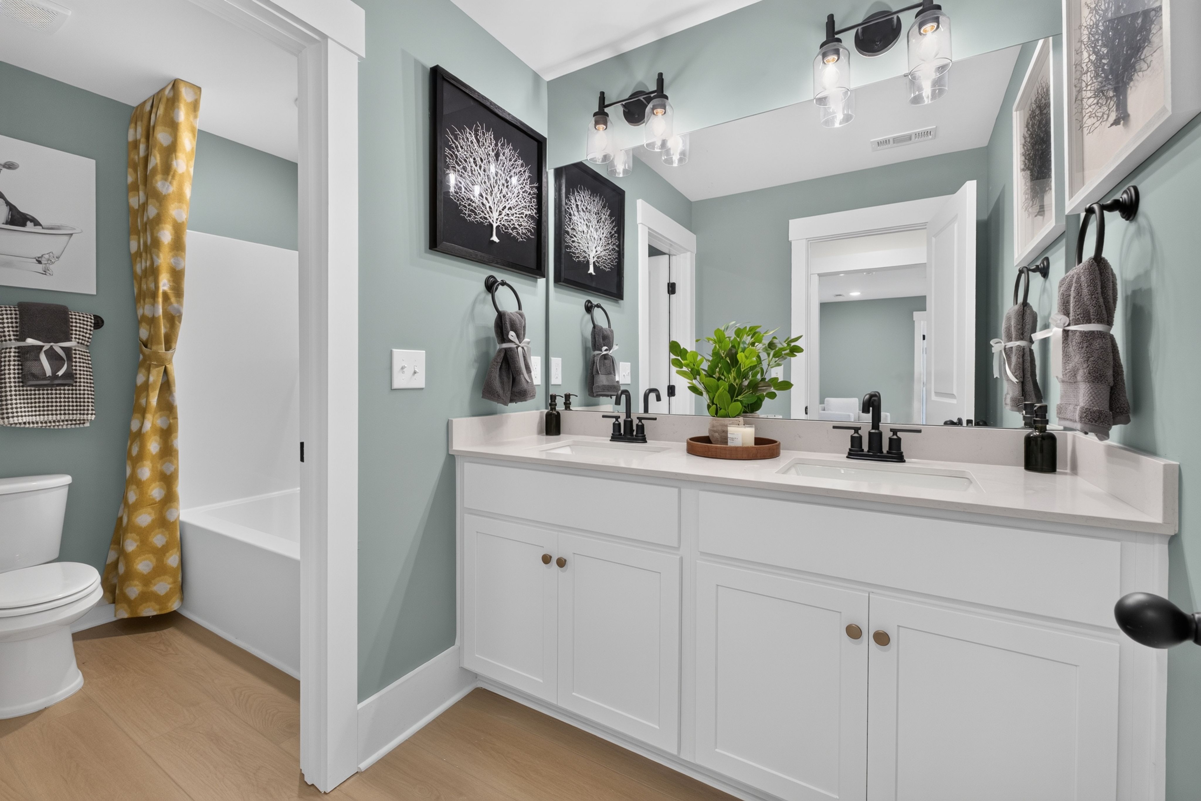 Bathroom with dual vanities and white cabinetry at Evergreen Mill by Davidson Homes in Madison, Alabama