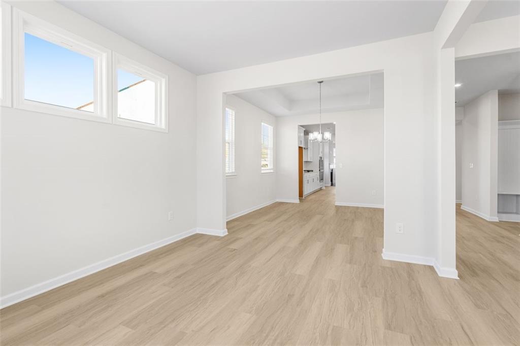 Bright open living area with large windows, hardwood floors, and archway in The Glenwood C by Davidson Homes, Hoschton, Georgia