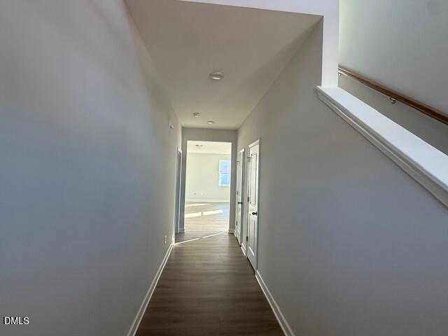 Bright hallway with white walls, hardwood floors, bedroom doors, and staircase in The Gavin B home, Lillington, NC