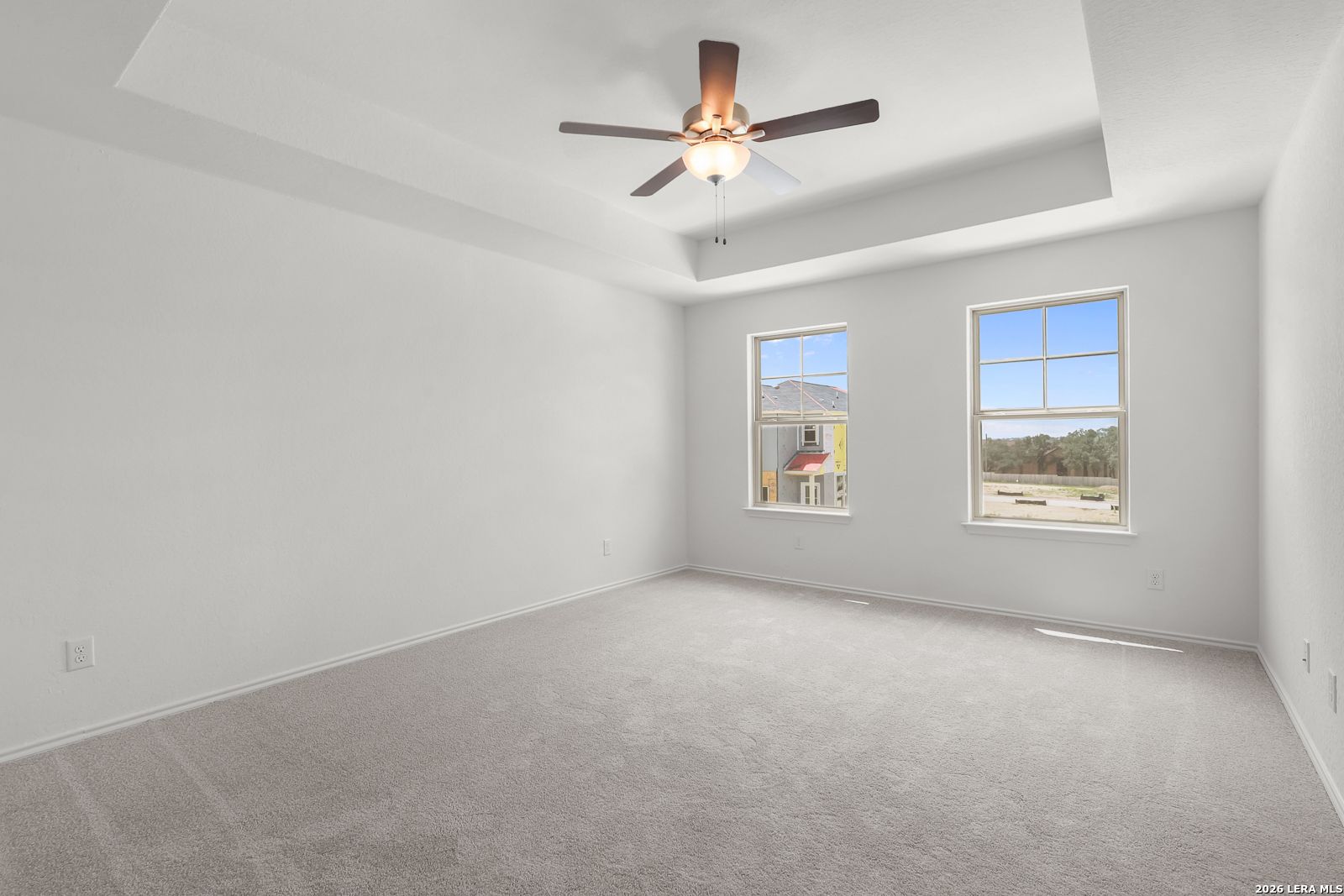Spacious bedroom with tray ceiling and ceiling fan in The Gillian C floor plan at Meadows at Oak Creek, San Antonio.