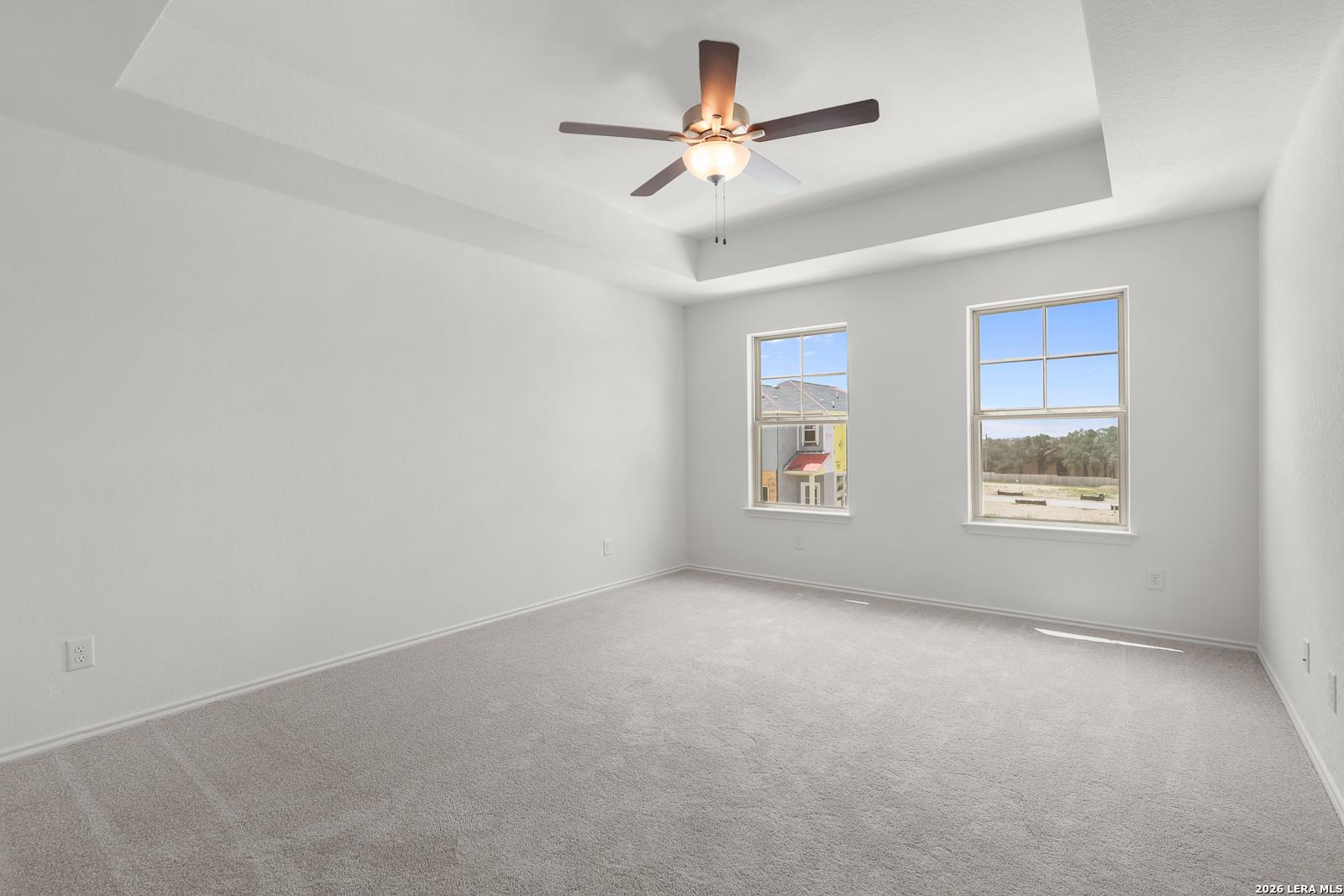 Spacious bedroom with tray ceiling and ceiling fan in The Gillian C floor plan at Meadows at Oak Creek, San Antonio.