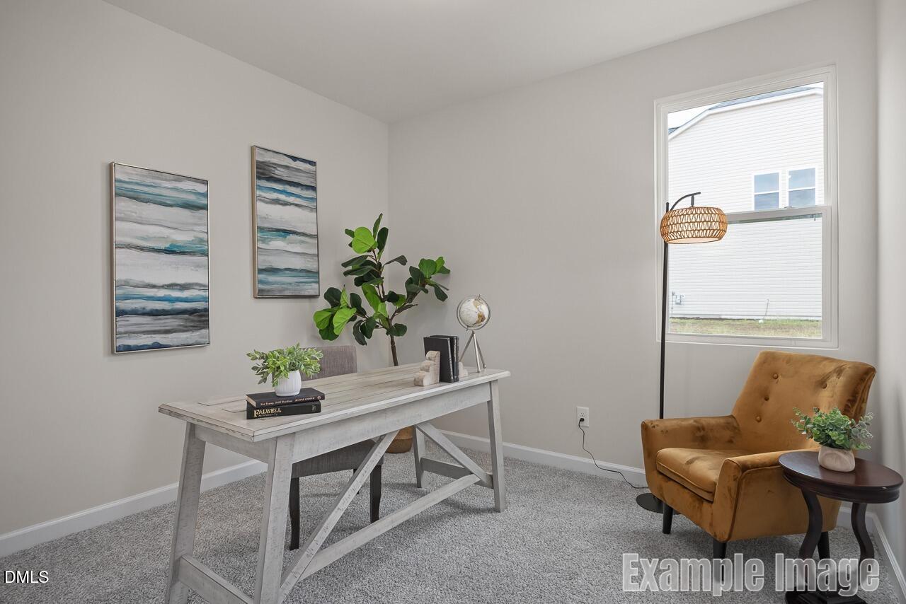 Cozy home office with farmhouse desk, orange velvet armchair, fiddle leaf fig, and abstract art in Davidson Homes The Carter C, Lillington, NC