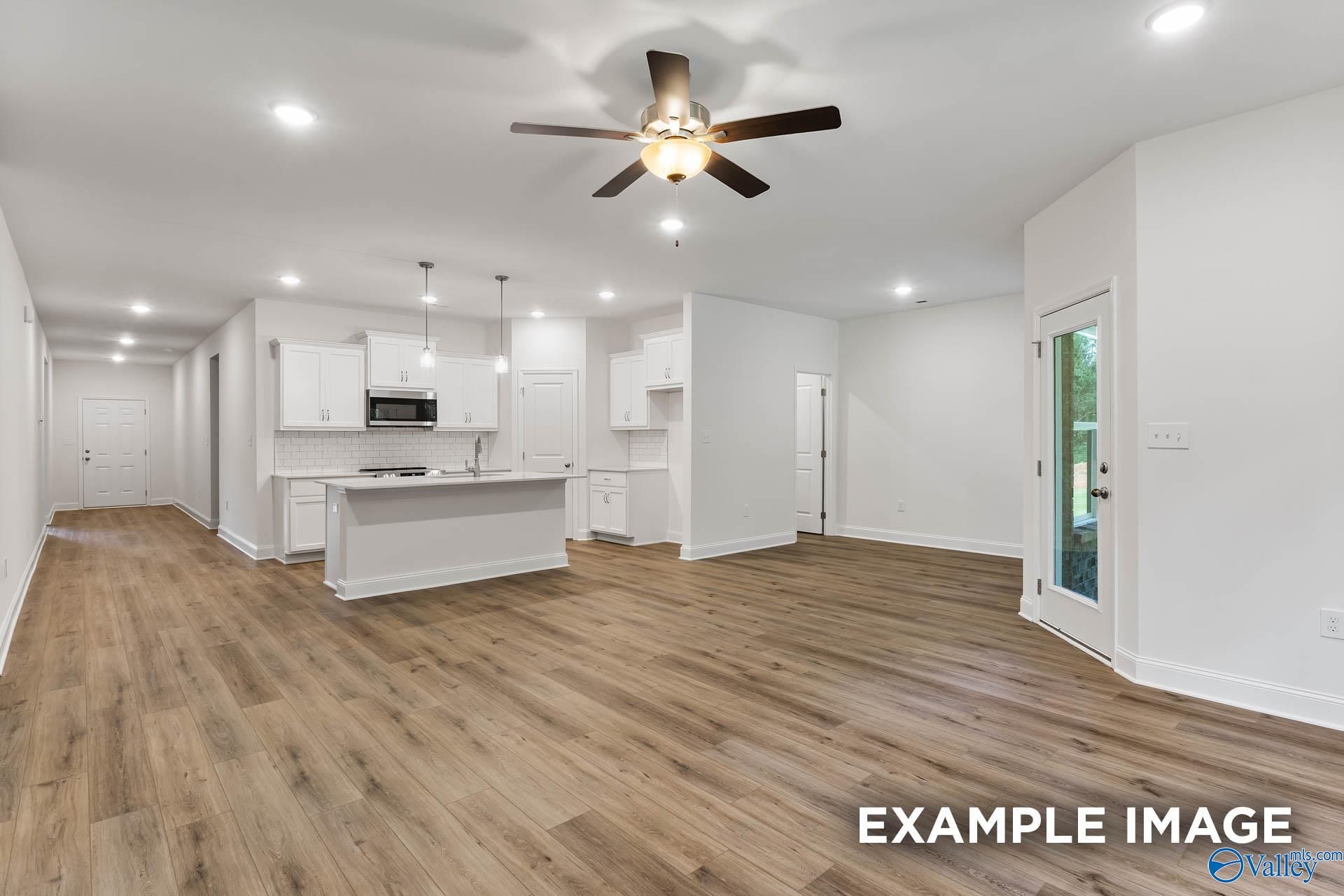 Open hallway and kitchen with white cabinets, island sink, hardwood floors, ceiling fan in Davidson Homes Daphne V, Athens, Alabama