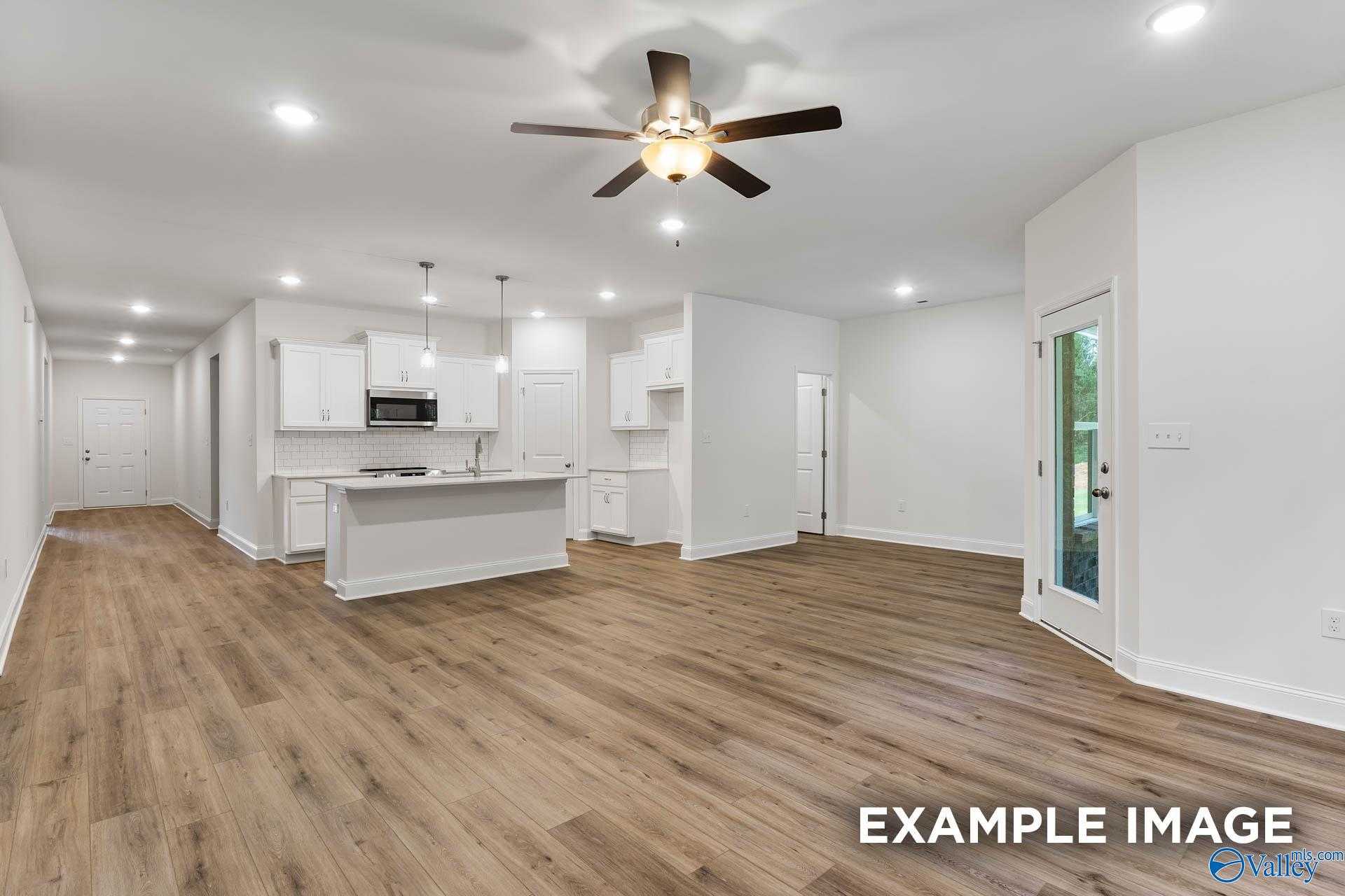 Open hallway and kitchen with white cabinets, island sink, hardwood floors, ceiling fan in Davidson Homes Daphne V, Athens, Alabama