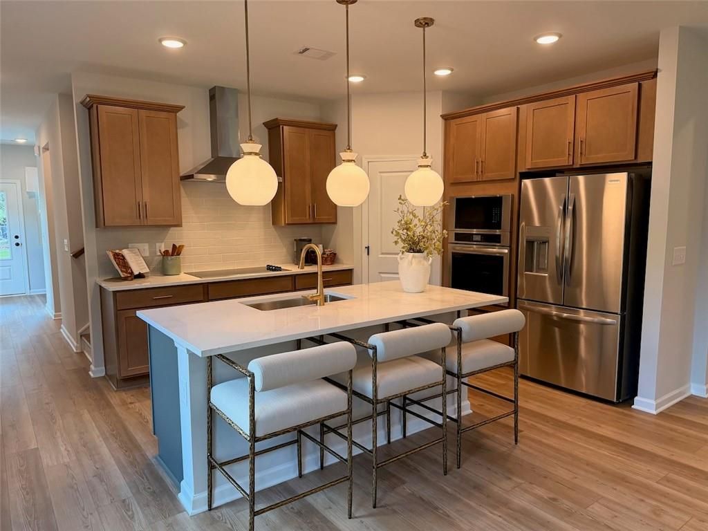 Modern kitchen island with white quartz countertop, gold pendant lights, and bar stools in Davidson Homes Pinecrest J, Cartersville GA