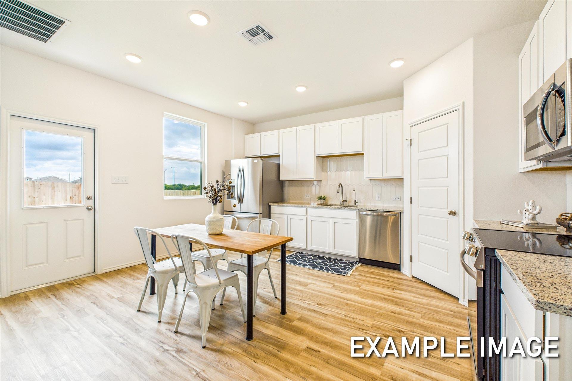Bright kitchen in The Trinity B with white cabinets, stainless appliances, granite counters, and dining nook in San Antonio home
