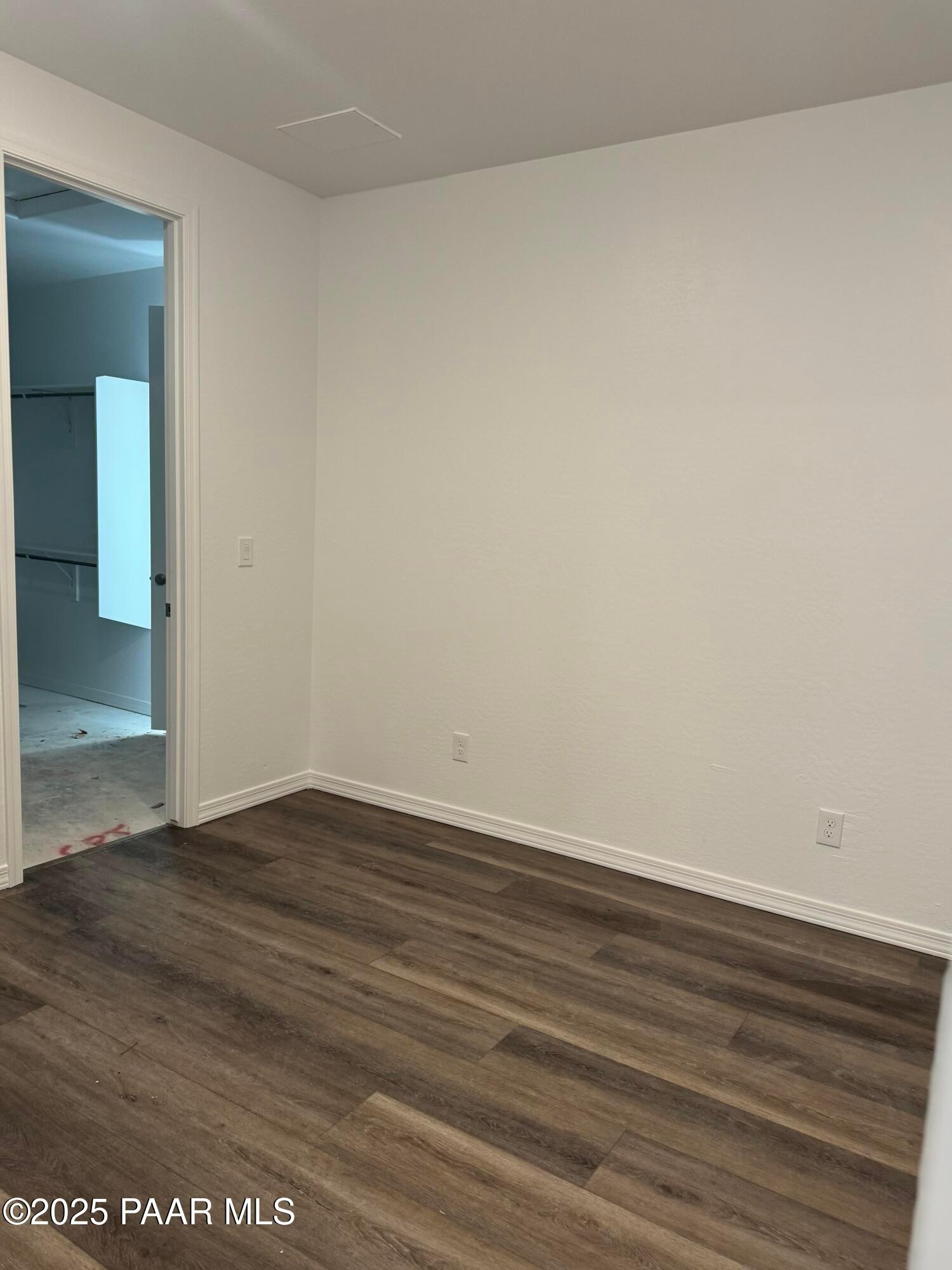 Empty secondary bedroom with hardwood floors, walk-in closet, and en-suite bathroom in Davidson Homes The Sunrise II A, Prescott, Arizona