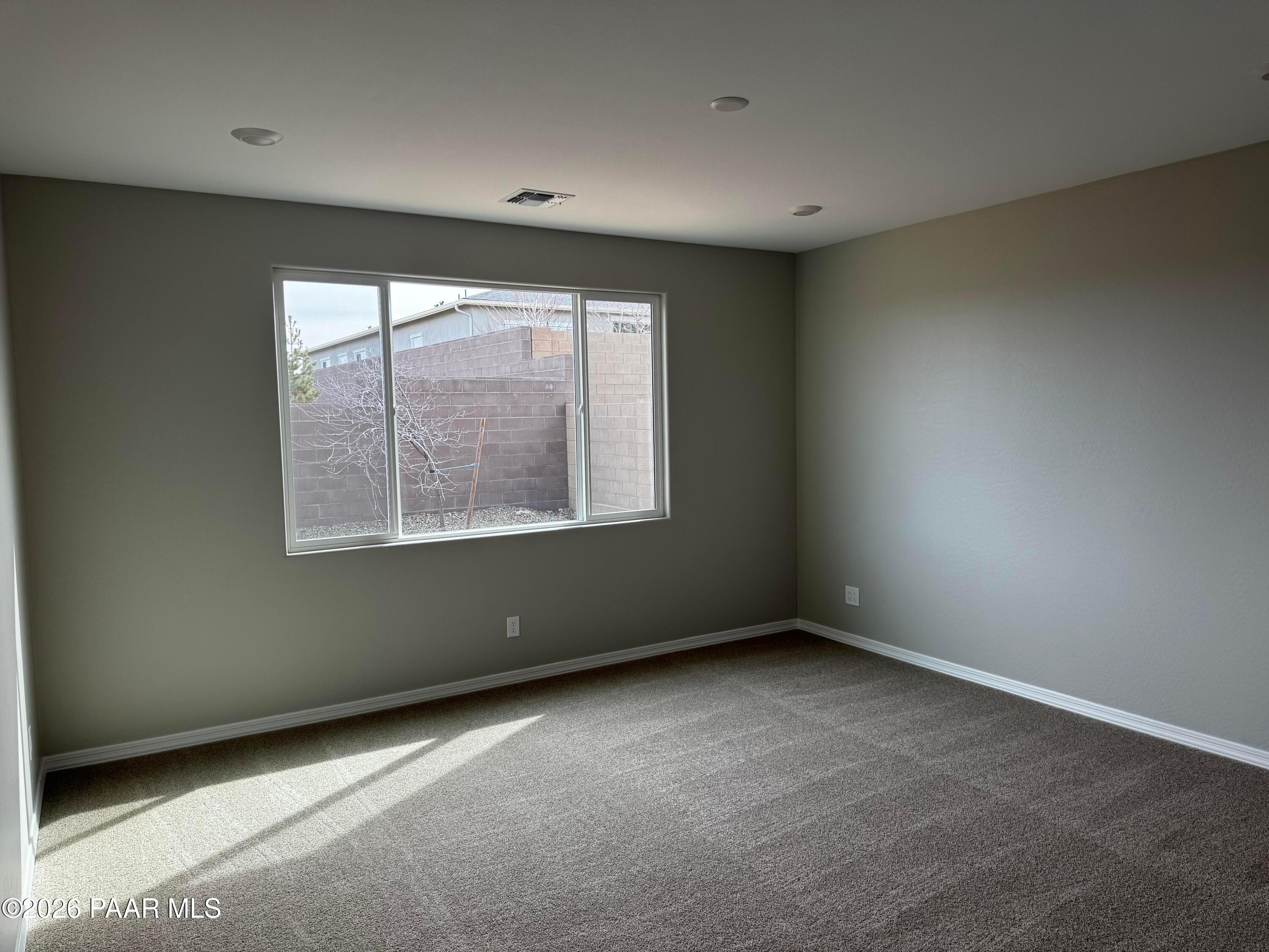 Sunlit empty bedroom with large window, neutral gray walls, beige carpet in Davidson Homes Durango II B, Prescott AZ