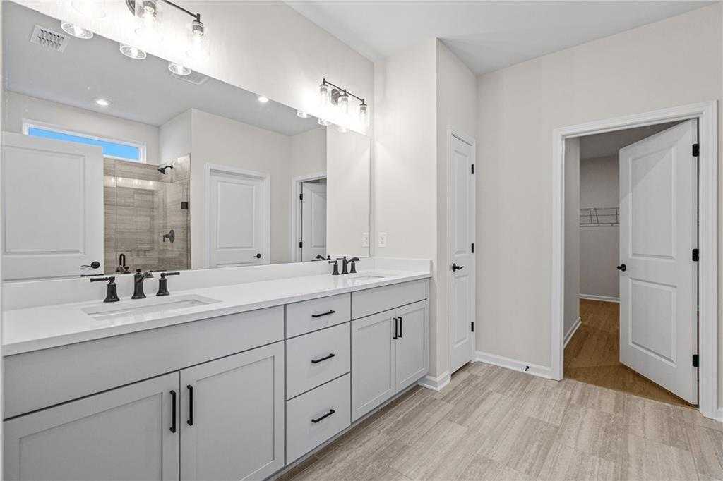 Modern master bathroom featuring double vanity, quartz counters, and walk-in shower in Davidson Homes The Edison A, Loganville, GA