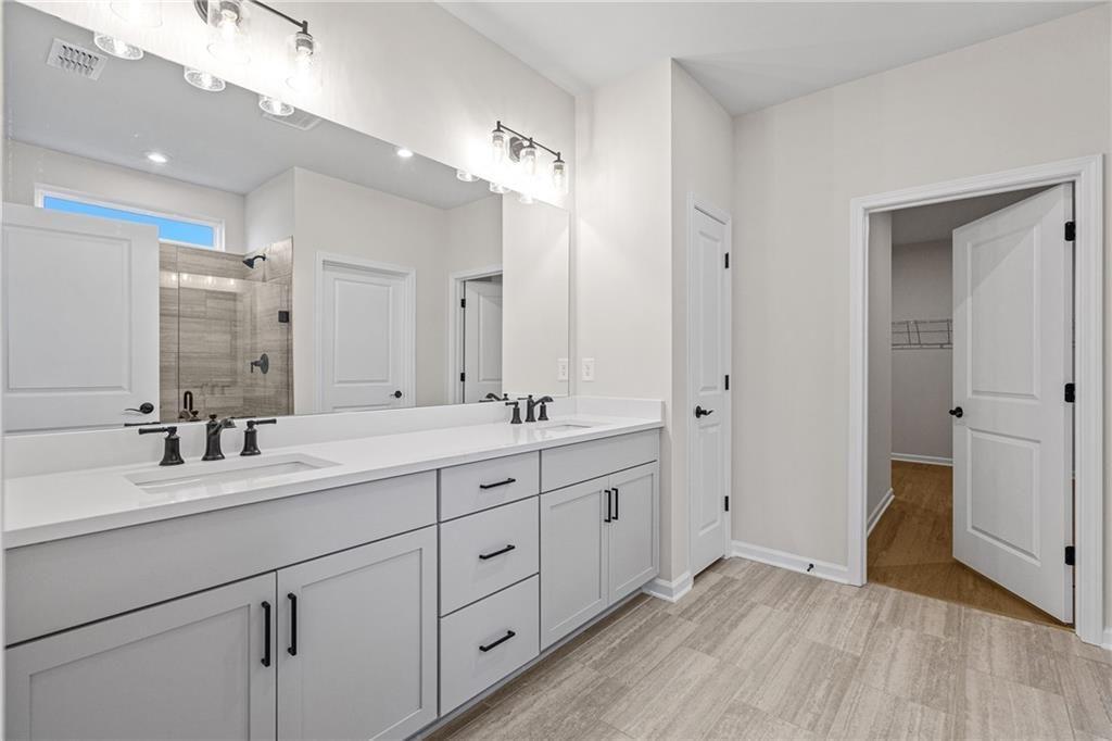 Modern master bathroom featuring double vanity, quartz counters, and walk-in shower in Davidson Homes The Edison A, Loganville, GA