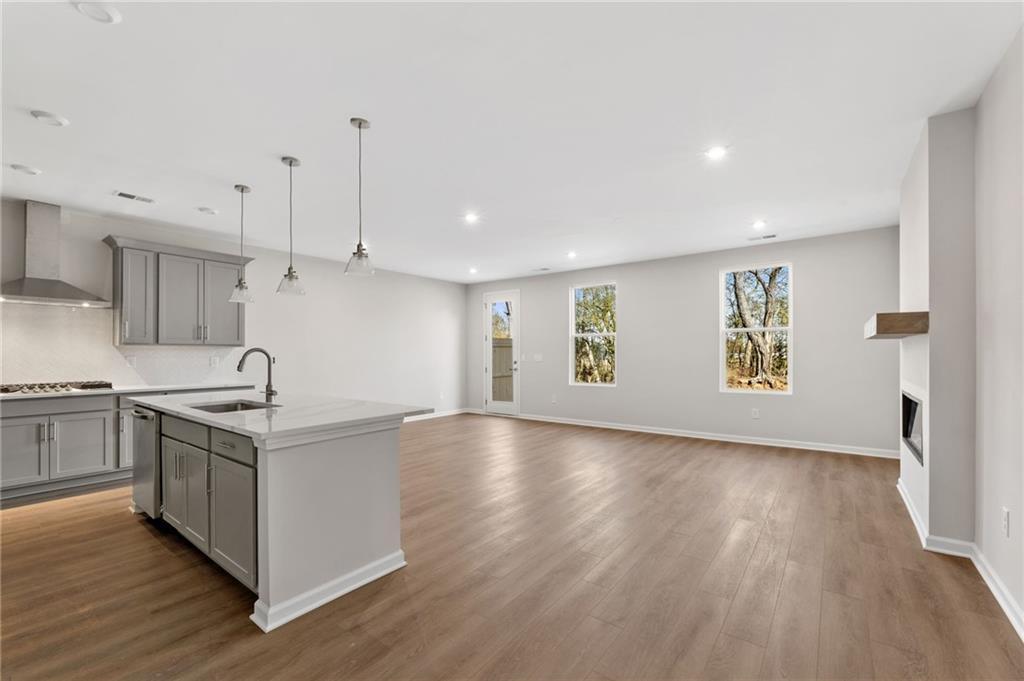 Open-concept kitchen with gray cabinets, white island, stainless appliances, and adjacent family room fireplace in Davidson Homes The Marion A, Winder, GA