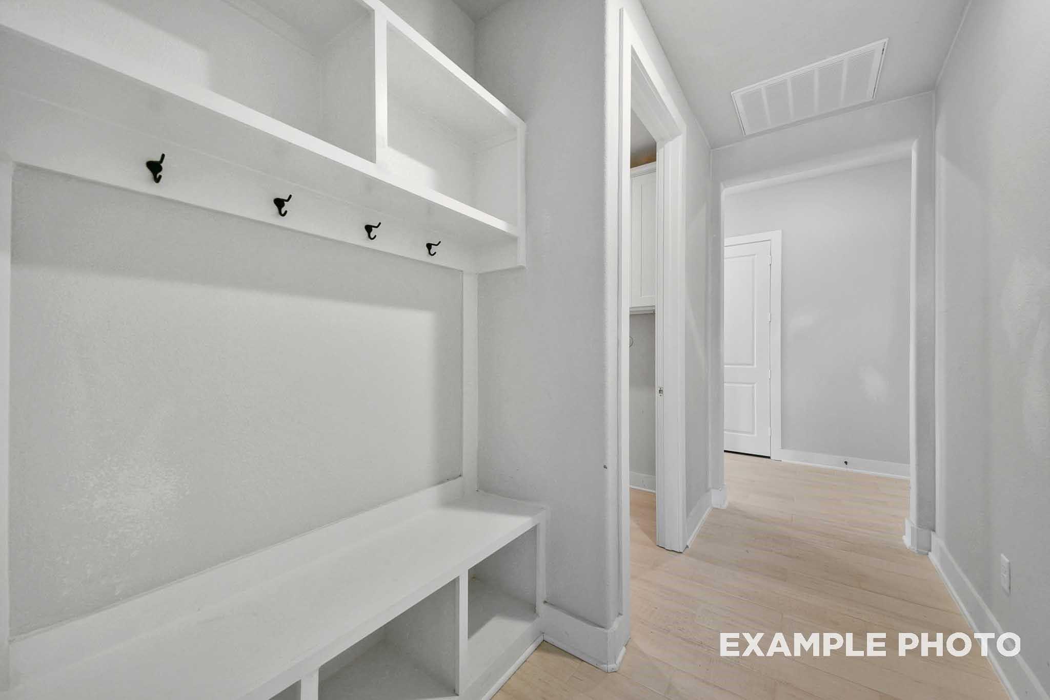 White mudroom with built-in shelves, coat hooks, and bench in Davidson Homes The George A, Lago Mar, Texas City