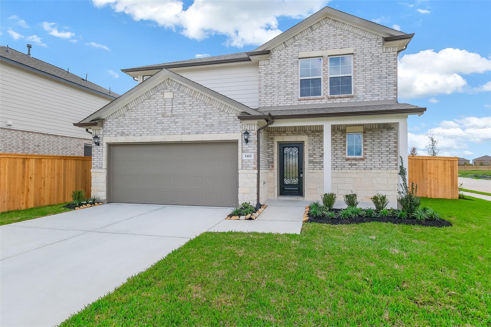 Modern two-story brick home with 2-car garage, front porch, and landscaped yard in Emberly, Beasley, Texas - Davidson Homes The Tierra B