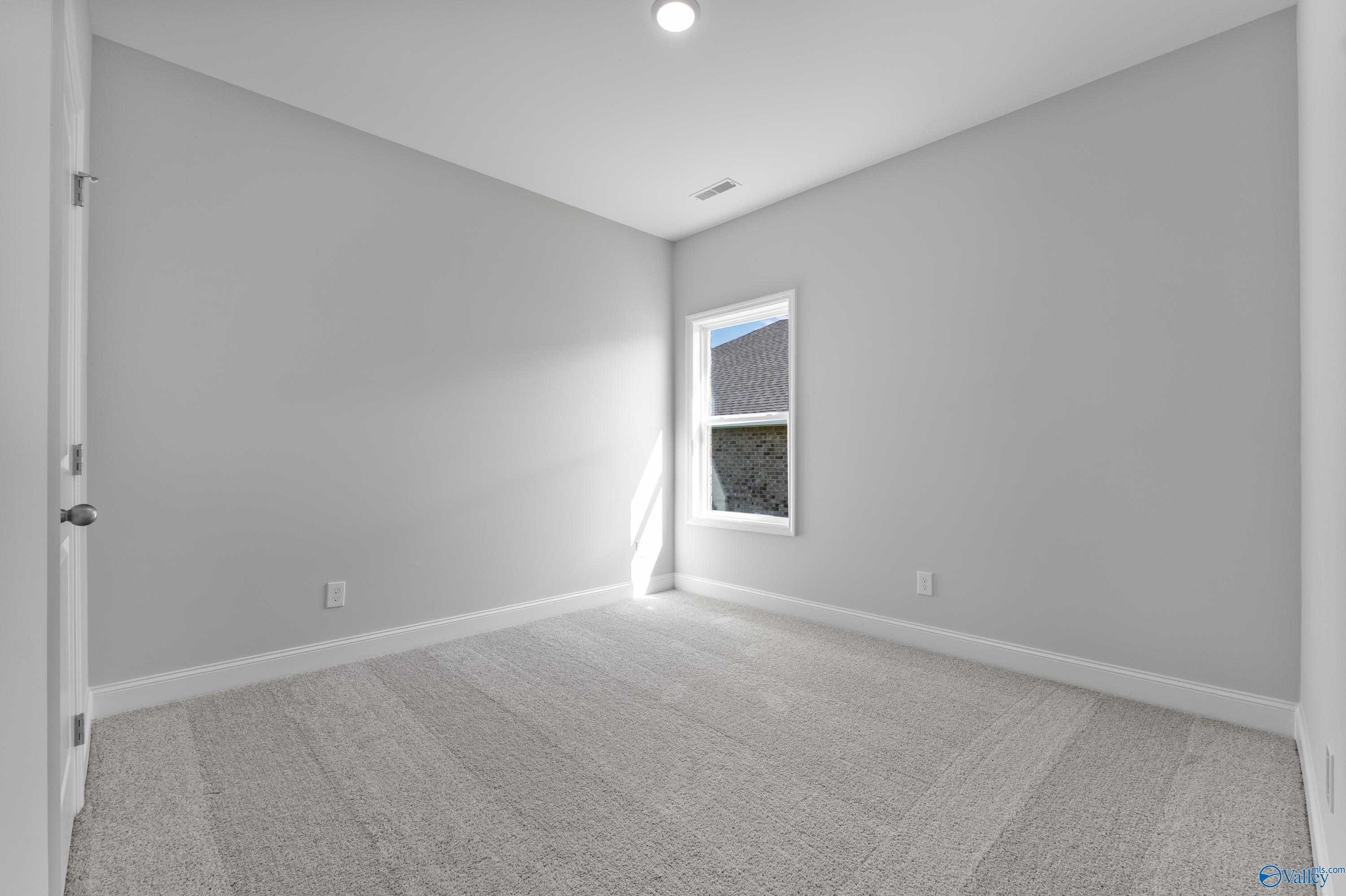Bright bedroom with neutral gray walls, plush carpet floor, and sunny window in Davidson Homes The Franklin C, Toney, Alabama