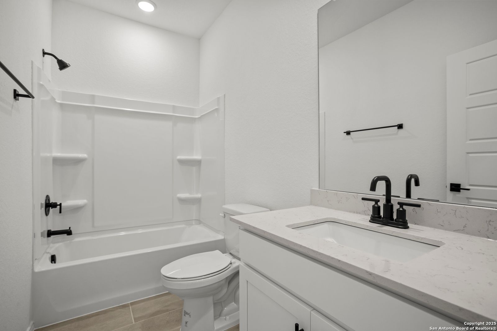 Modern white bathroom with quartz vanity, deep tub, walk-in shower in Davidson Homes The Daphne K, San Antonio