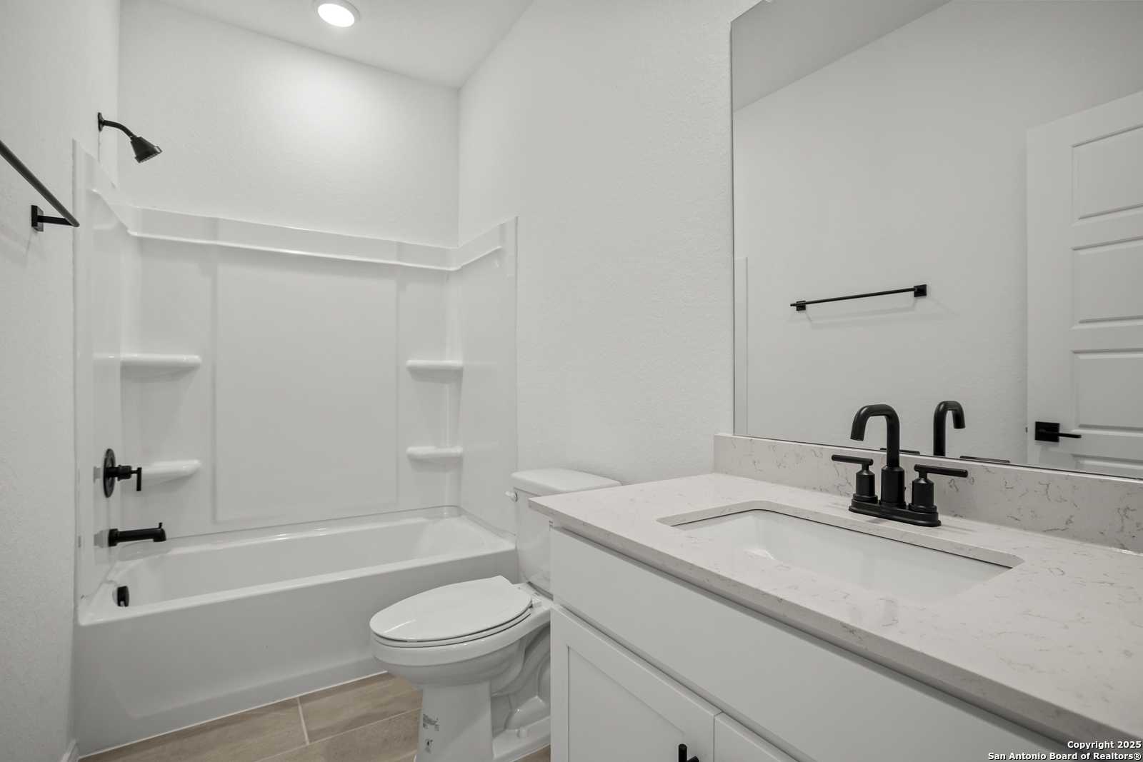 Modern white bathroom with quartz vanity, deep tub, walk-in shower in Davidson Homes The Daphne K, San Antonio